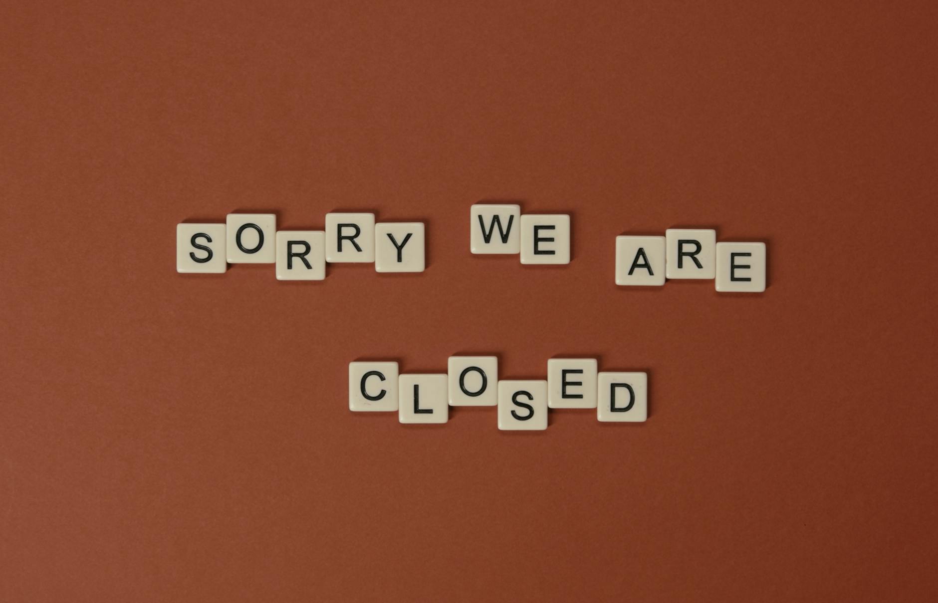 Scrabble tiles on a brown surface forming the phrase 'Sorry We Are Closed' with copy space. - bad apology examples