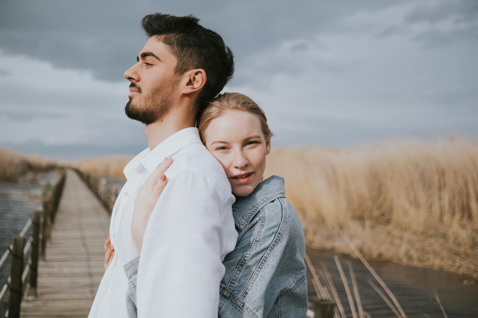 An intimate portrait of a couple embracing on a wooden bridge surrounded by nature. - build trust couples