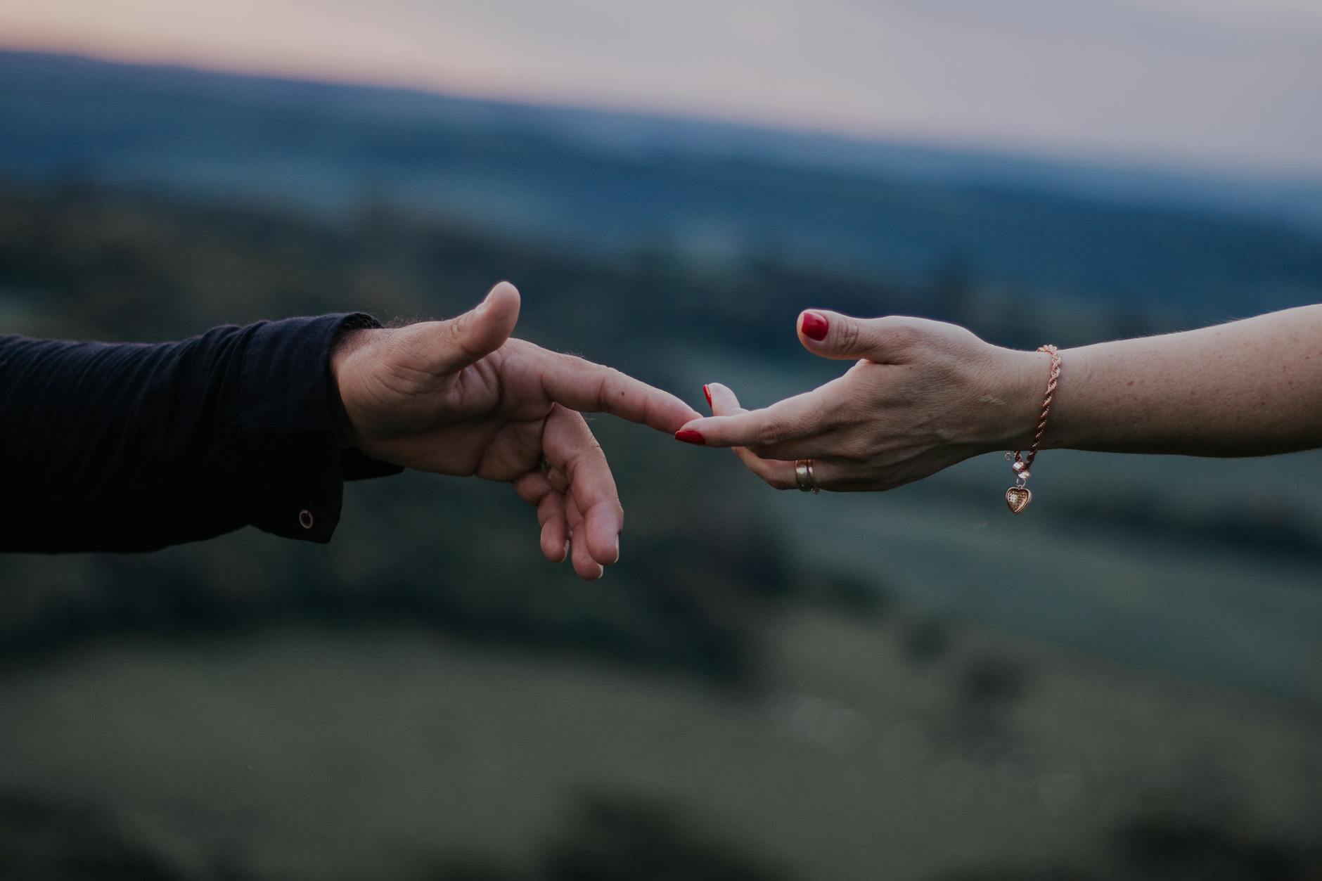 A romantic moment with hands reaching out in a peaceful outdoor setting captured at twilight. - casual to committed relationship