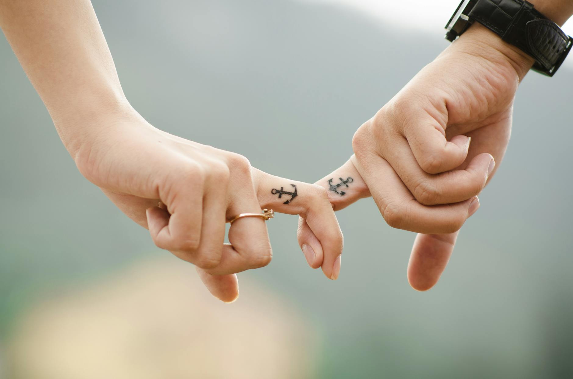 Close-up of a couple holding hands, featuring anchor tattoos symbolizing love and connection. - casual to committed relationship