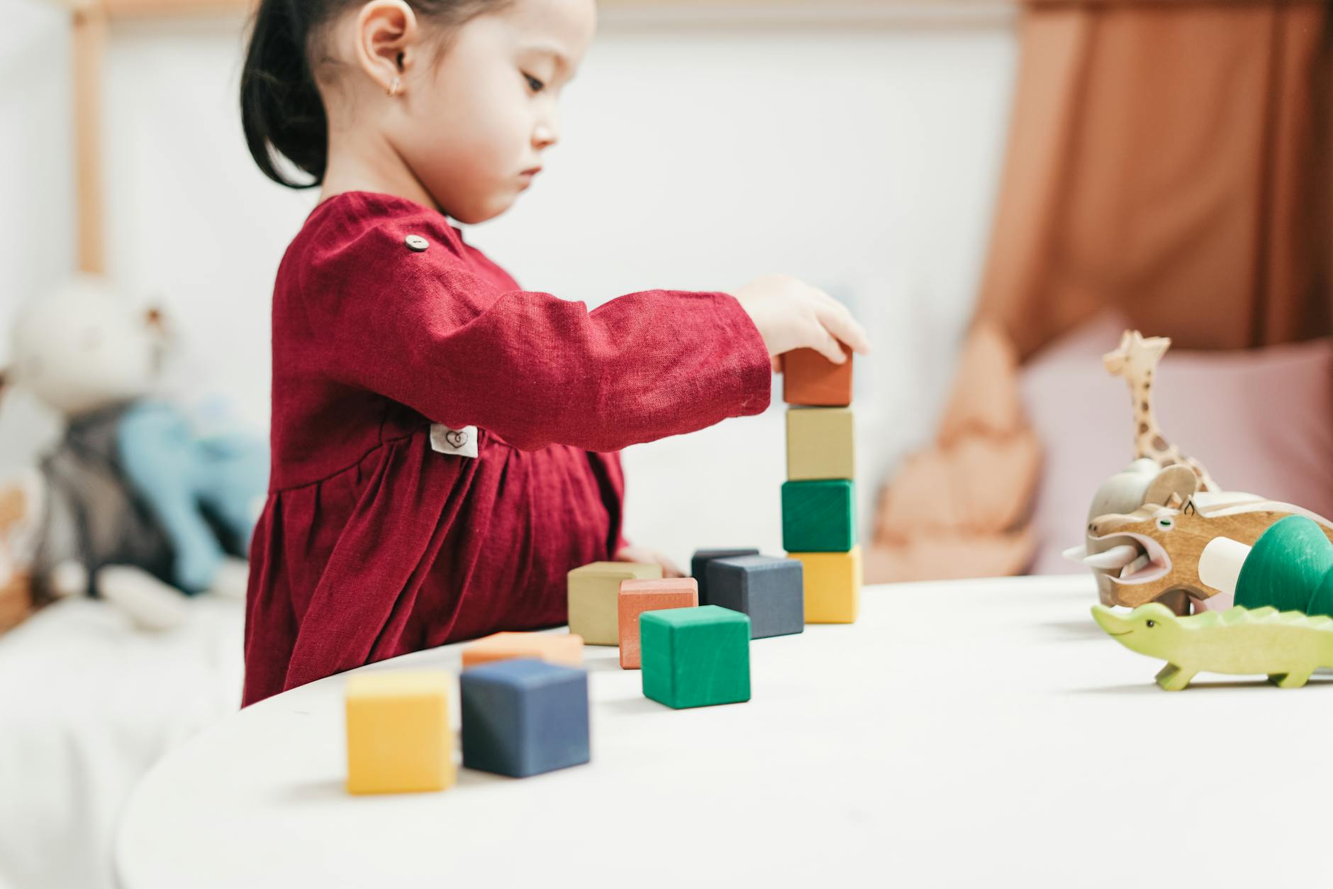 A young girl engaging with colorful wooden blocks, fostering creativity and learning in a playroom. - child development milestones