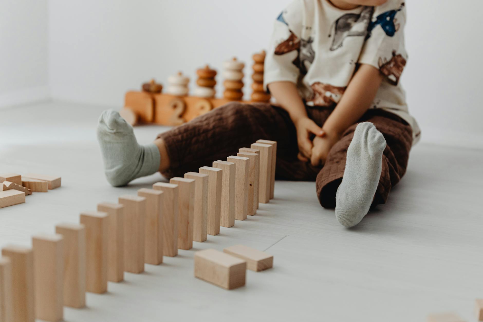 A young child sits indoors playing with wooden blocks, emphasizing creativity and learning. - child development milestones