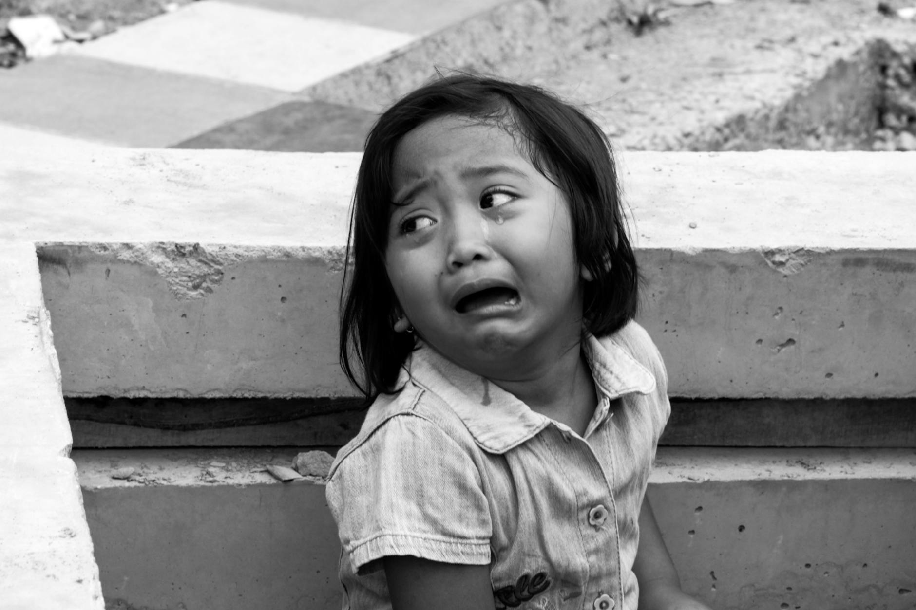 Emotional black and white photo of a crying child in an urban environment. - child emotional changes