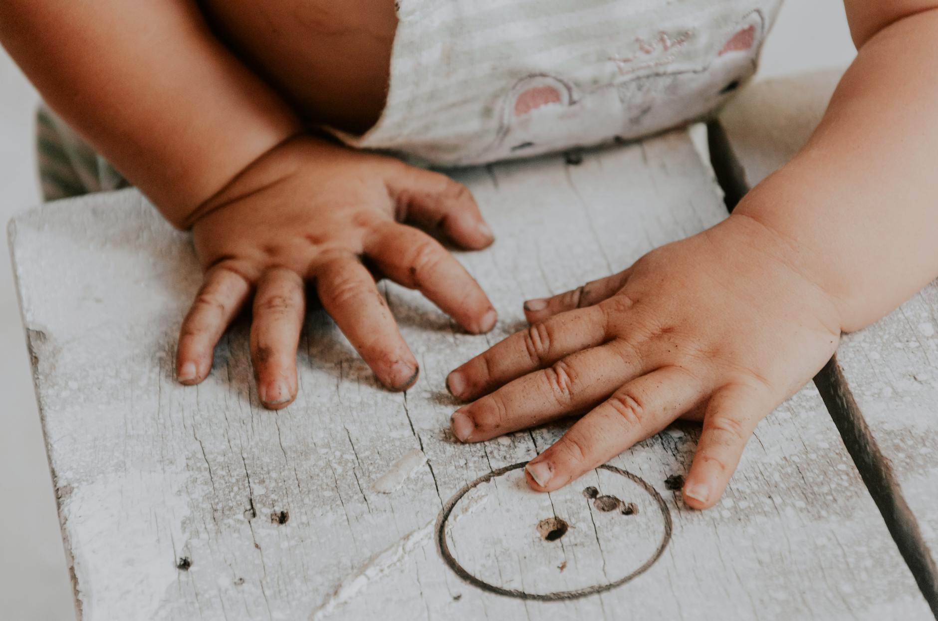 Adorable toddler exploring with dirty hands on a rustic wooden surface. - child growth spurt