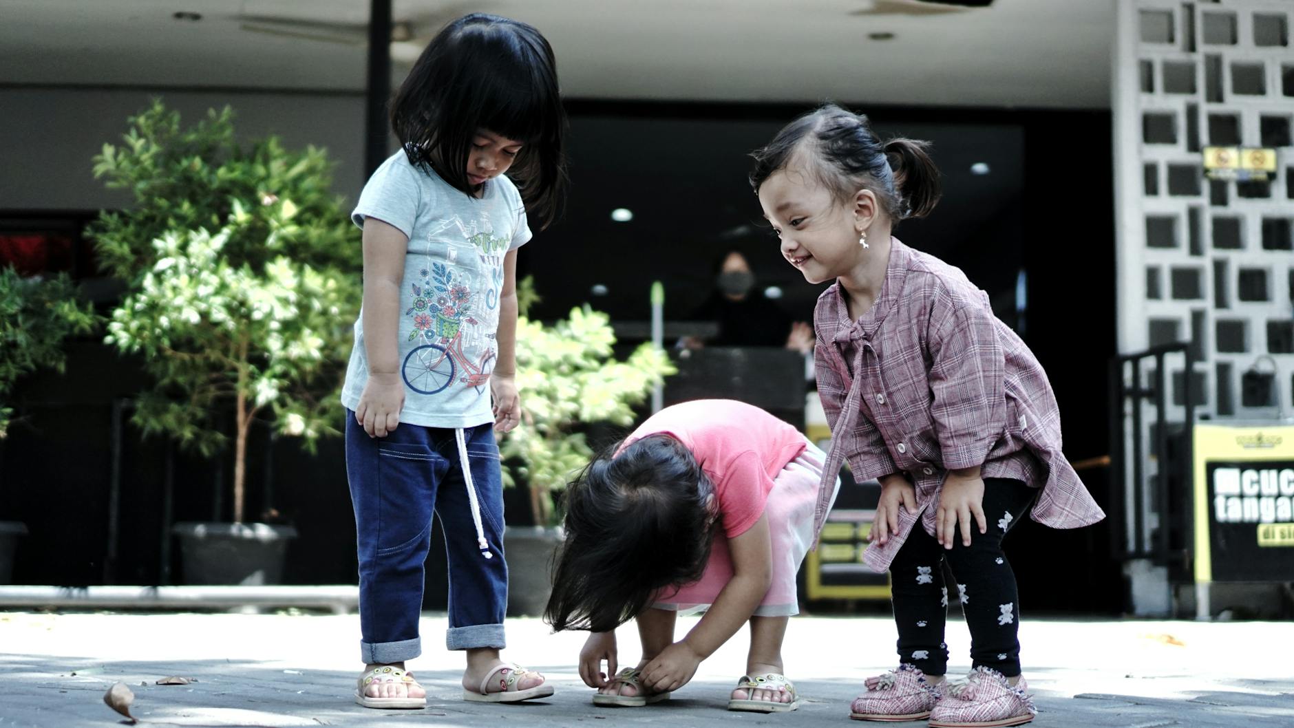 Three Asian girls joyfully playing together outside, capturing a moment of childhood fun. - child social skills