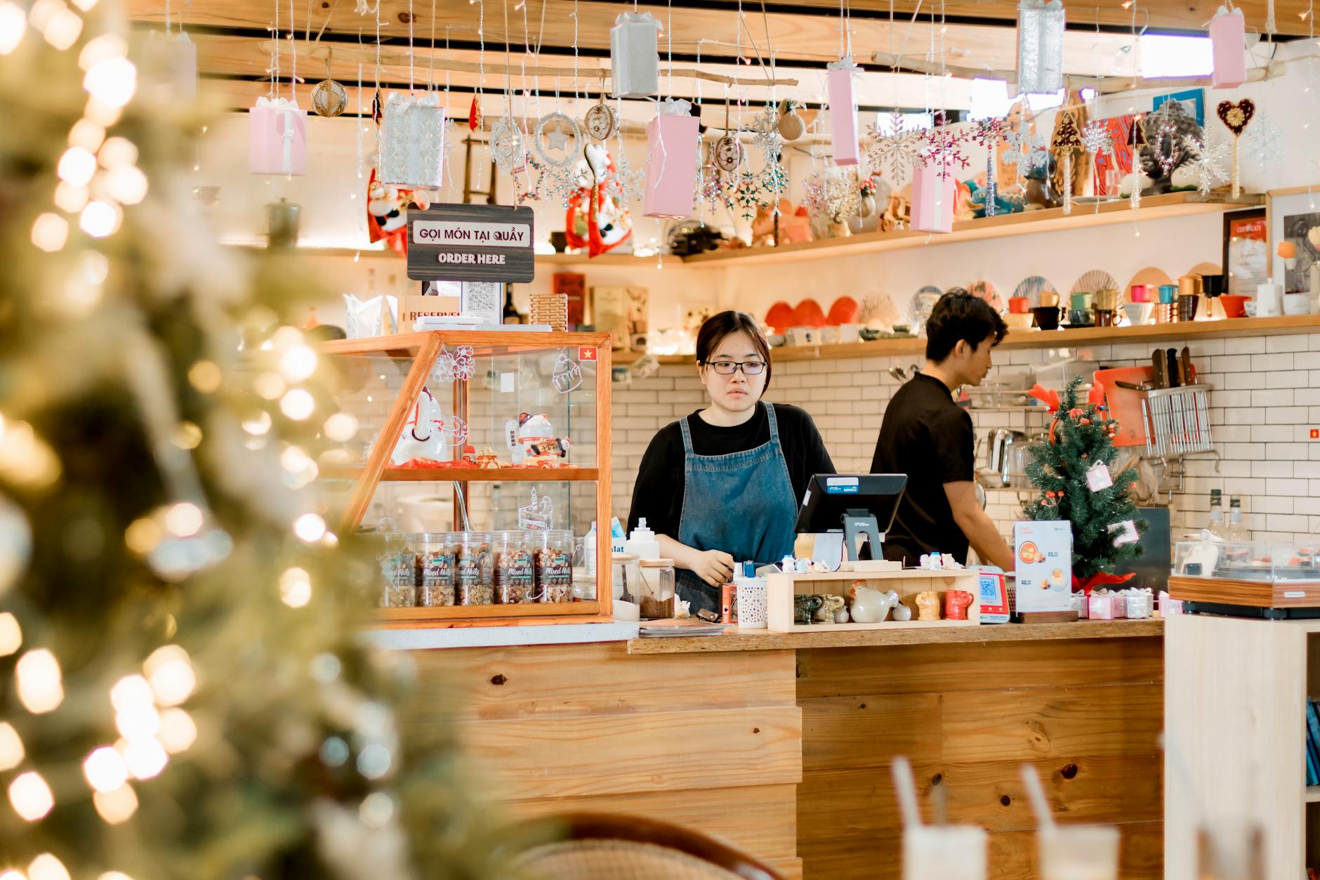 Cozy cafe with Christmas decor, barista at counter, warm atmosphere. - communicate needs busy season