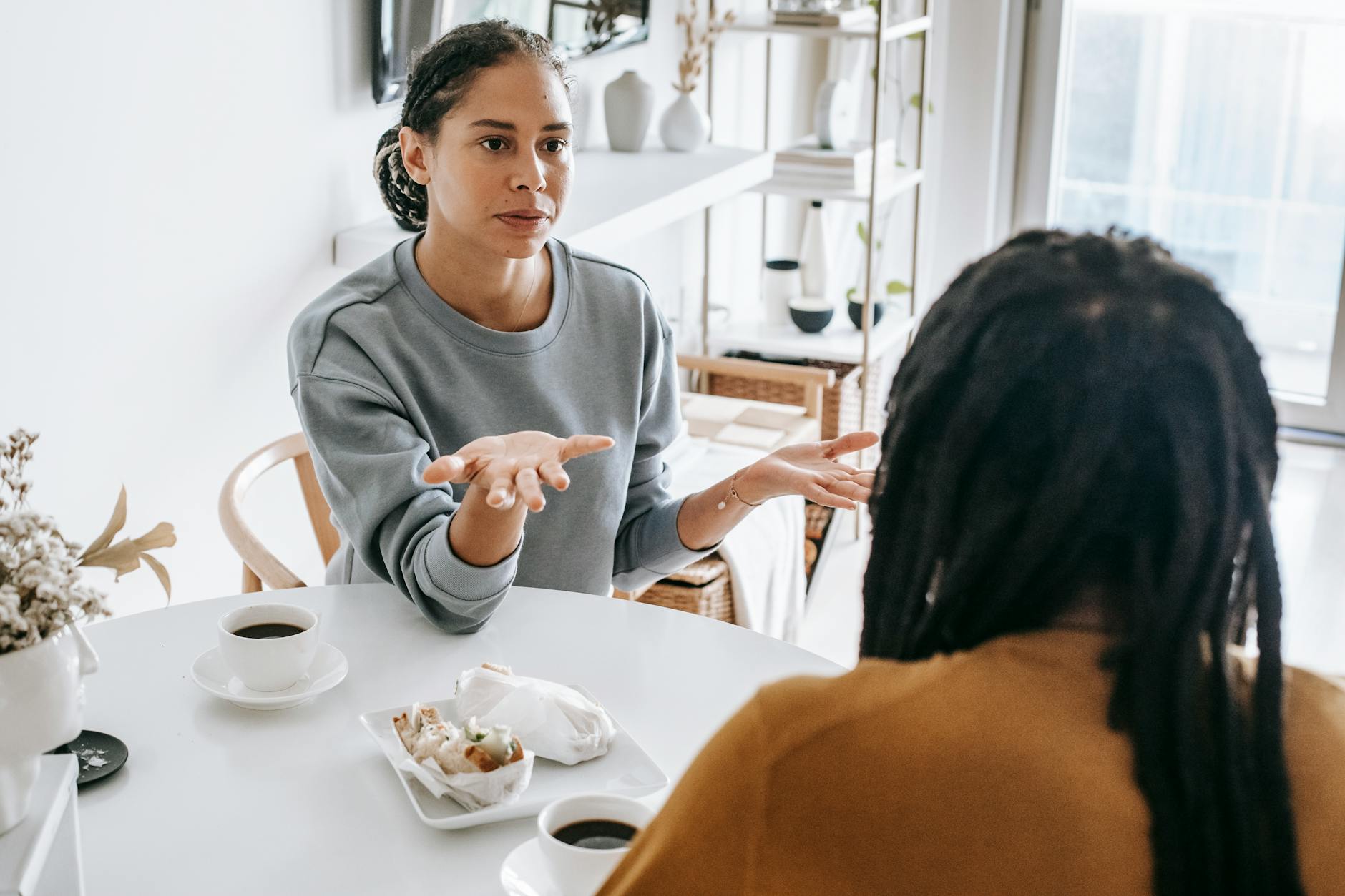 Young African American woman sitting at table and arguing with man in casual outfit in daylight - communicate needs relationship