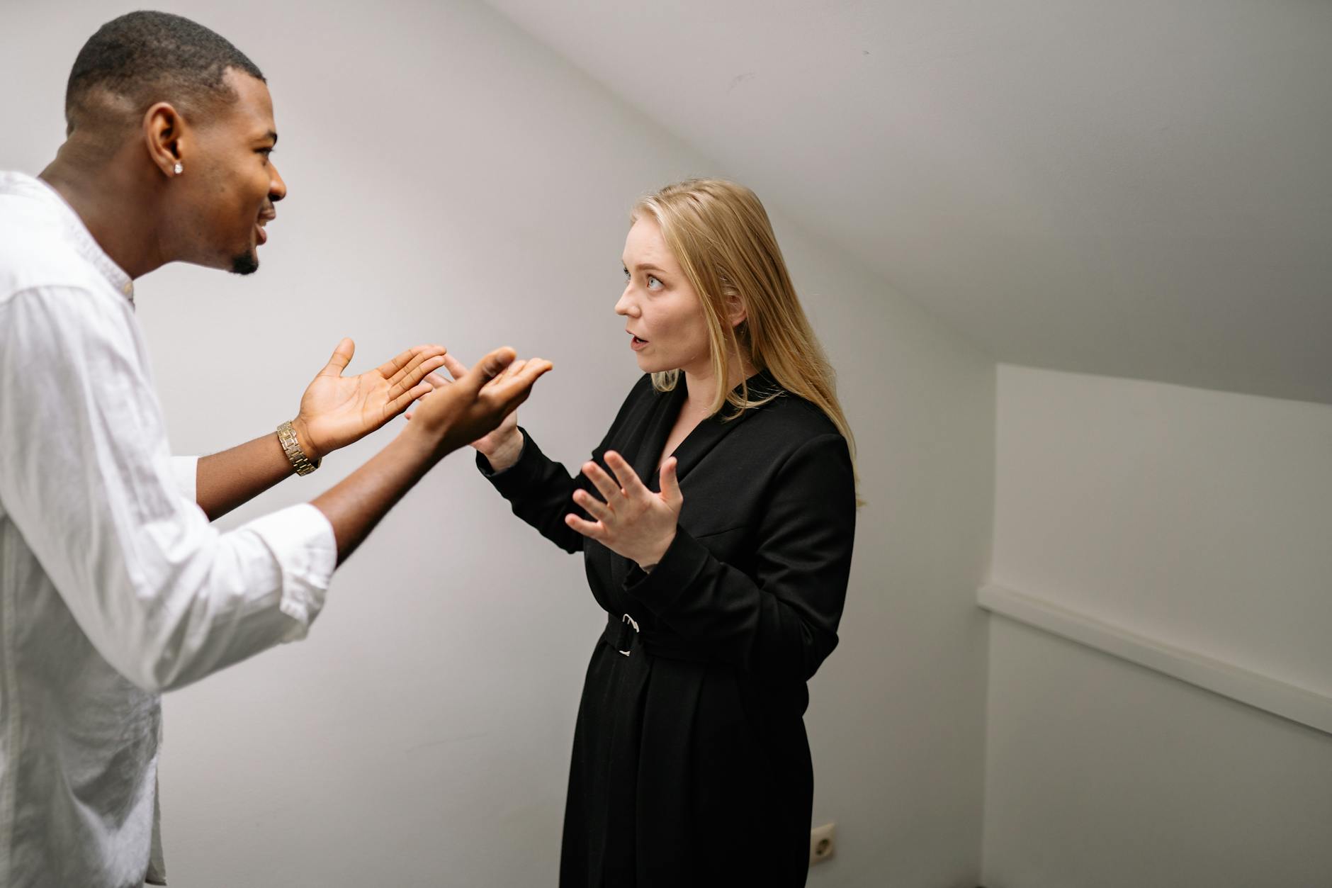 A man and woman having a heated discussion in a minimalistic indoor space. - conflict meaning