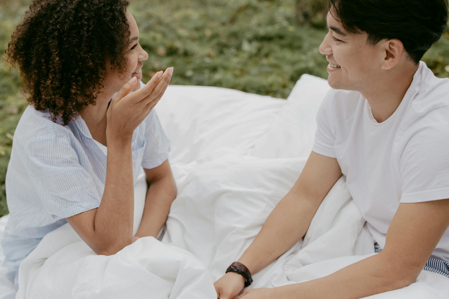 A happy couple smiling and chatting outdoors in a relaxed, romantic setting. - couple communication needs