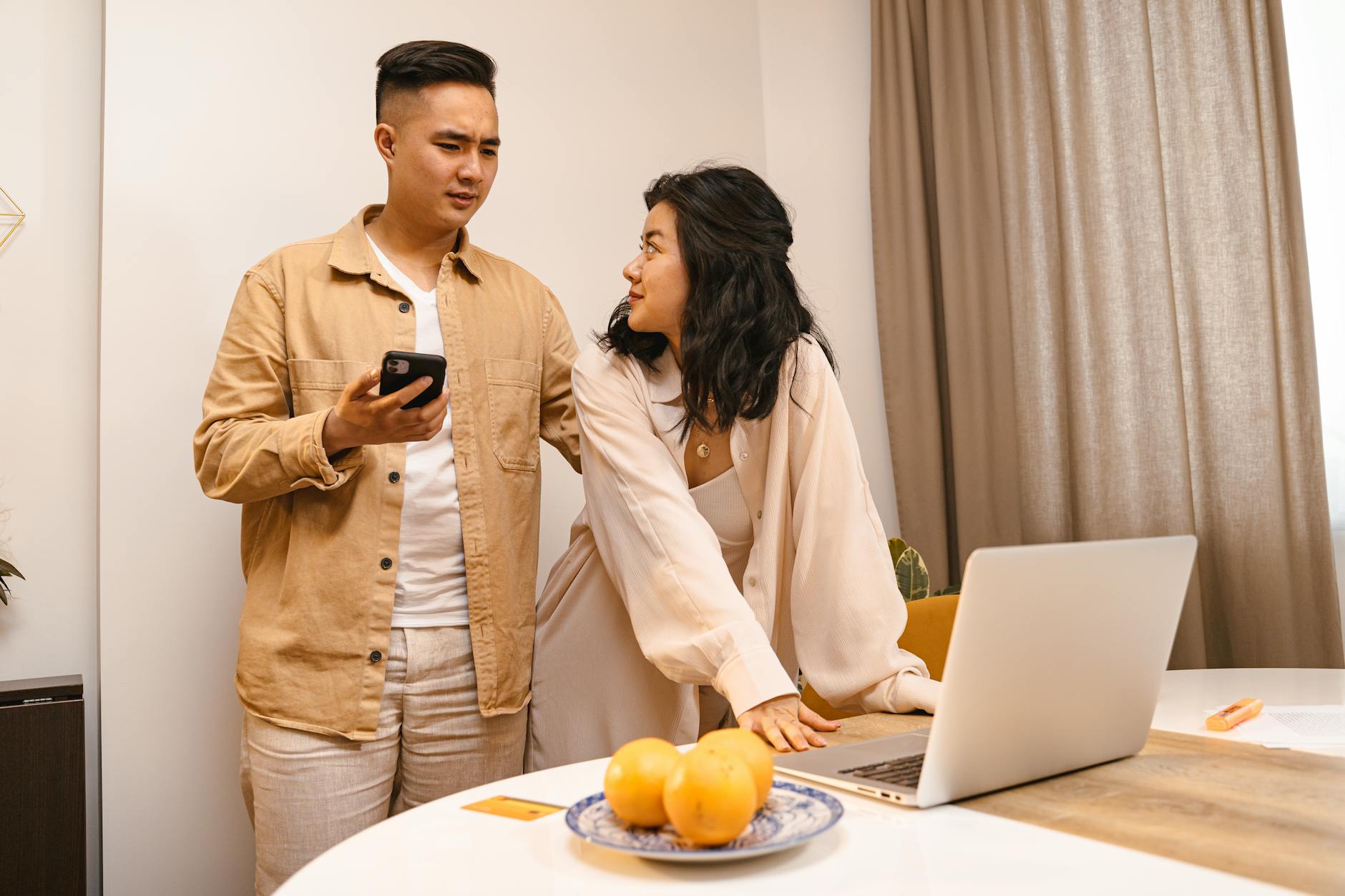 A couple in a modern home environment using a smartphone and laptop together. - couple communication needs