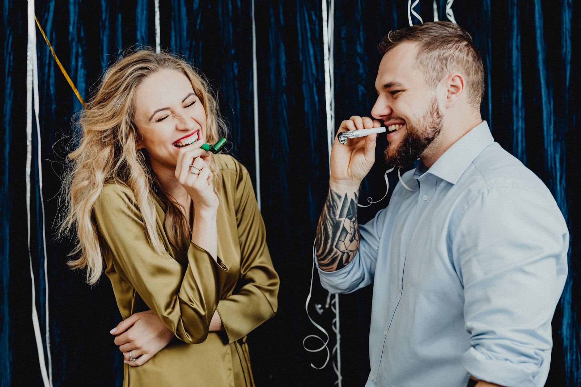 A joyful couple laughing and celebrating indoors with party favors and streamers. - couple resolutions