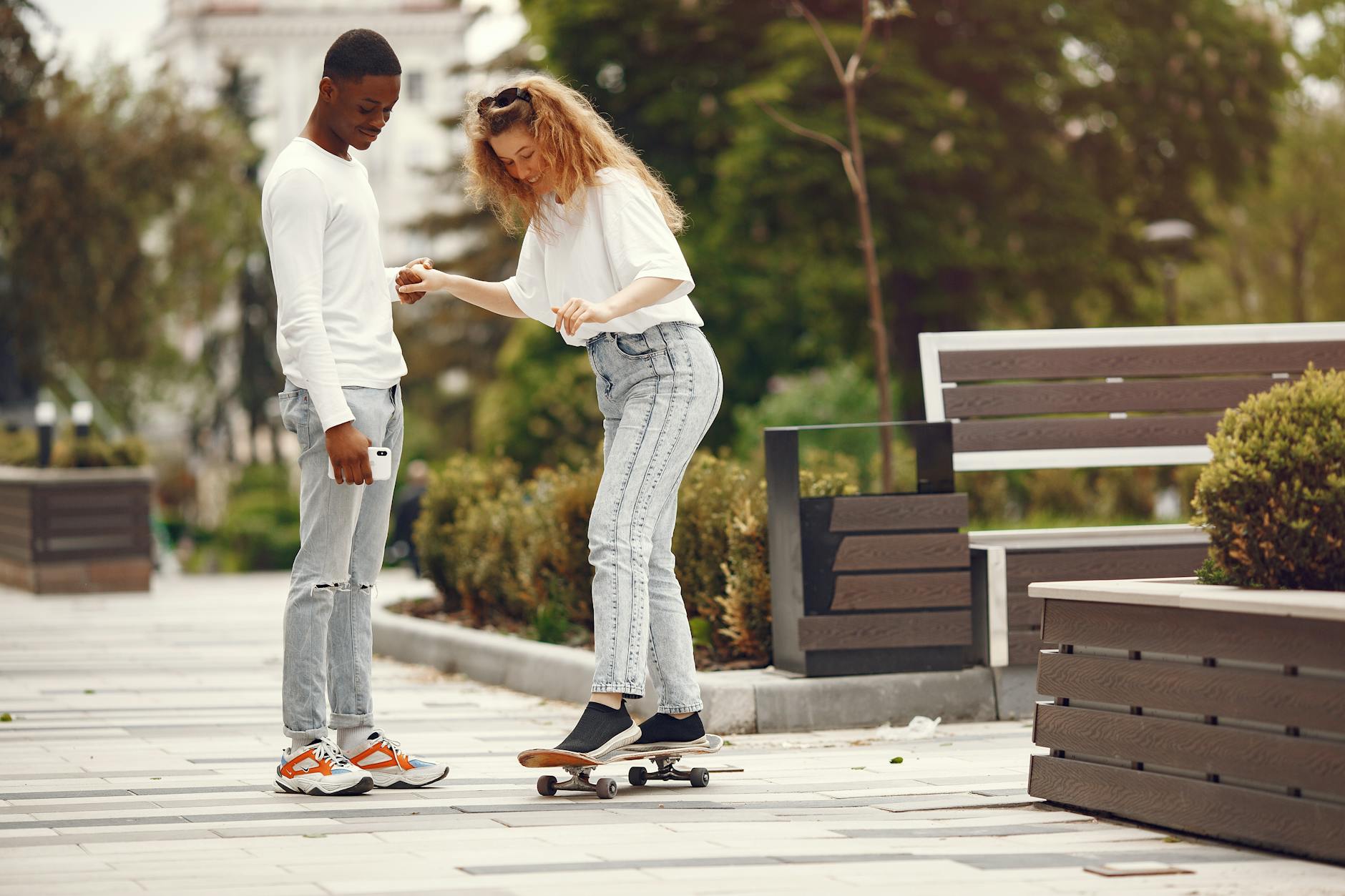 Interracial couple enjoying skateboarding together in a sunny park. - couple spring activities