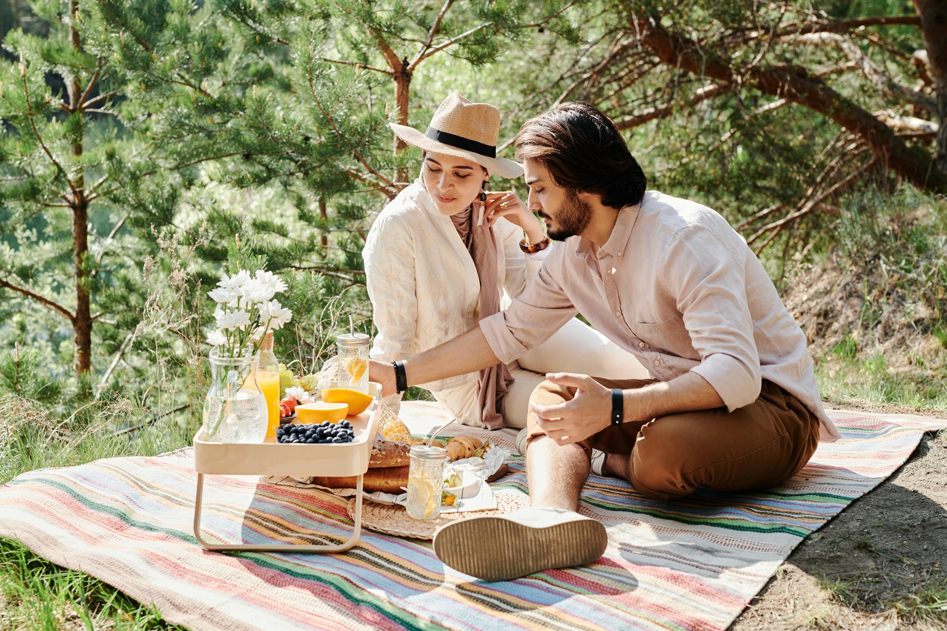 Couple enjoying a picnic outdoors with fresh fruits and drinks. - couple spring activities