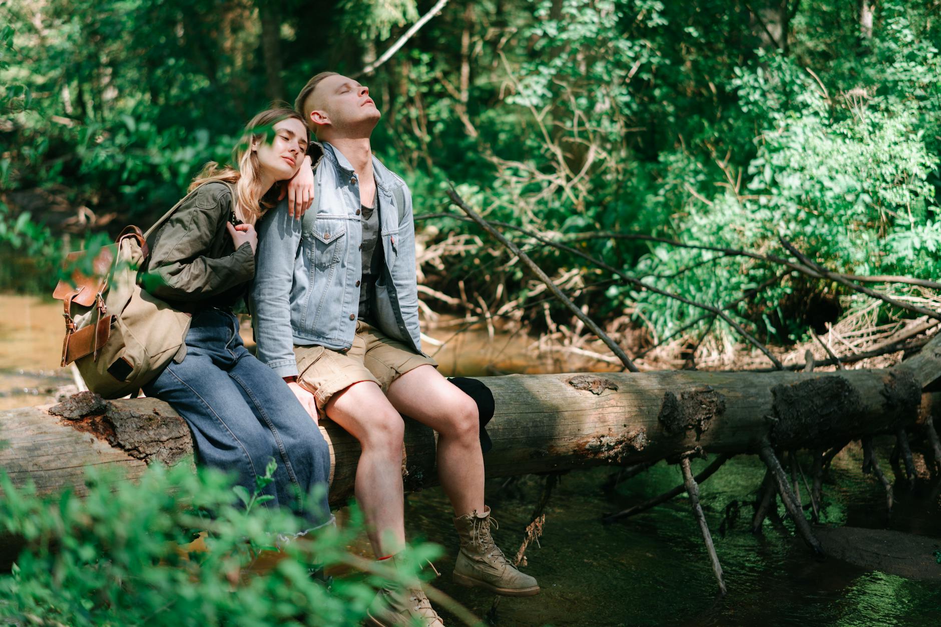 A loving couple enjoys a serene moment together on a log in a vibrant forest. - couple spring activities