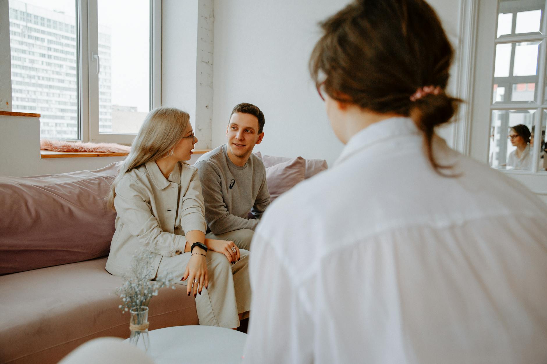 A couple engaged in a counseling session with a therapist in a modern indoor setting. - couples counseling benefits