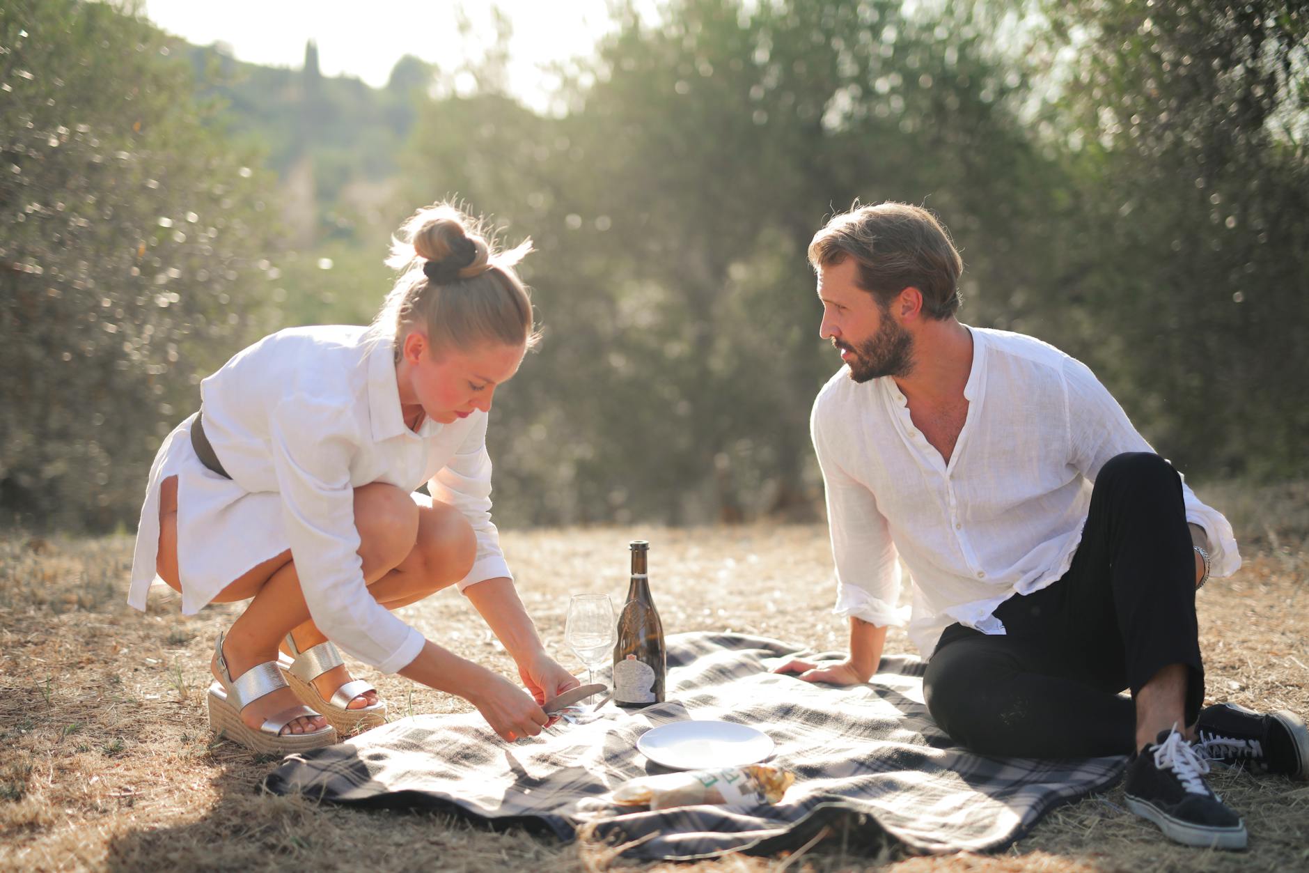 A couple enjoying a romantic picnic on a sunny day surrounded by nature, showcasing love and connection. - dating in 30s