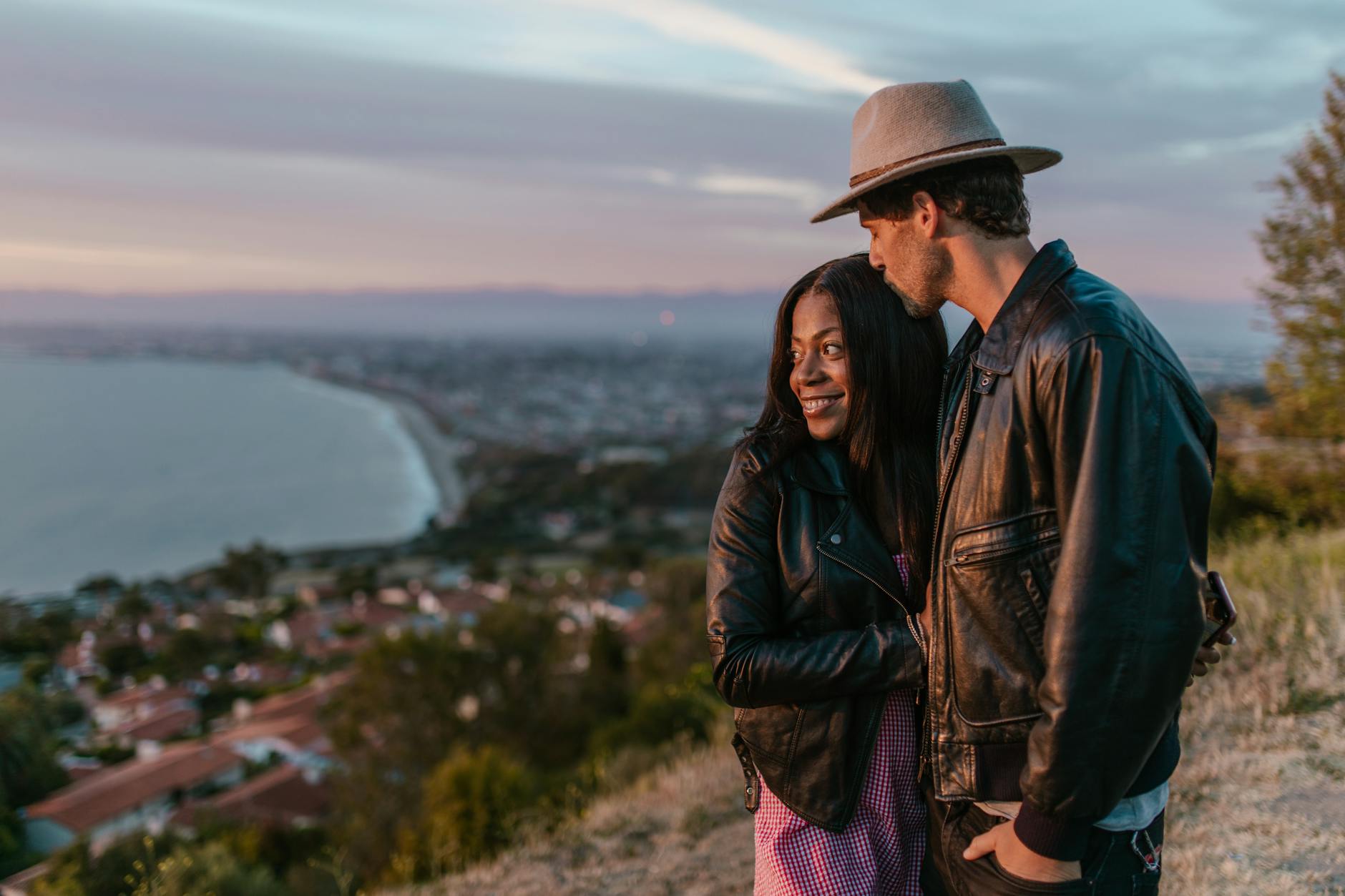 Couple embraces with a stunning coastal sunset backdrop, exuding romance and affection. - dating in 30s