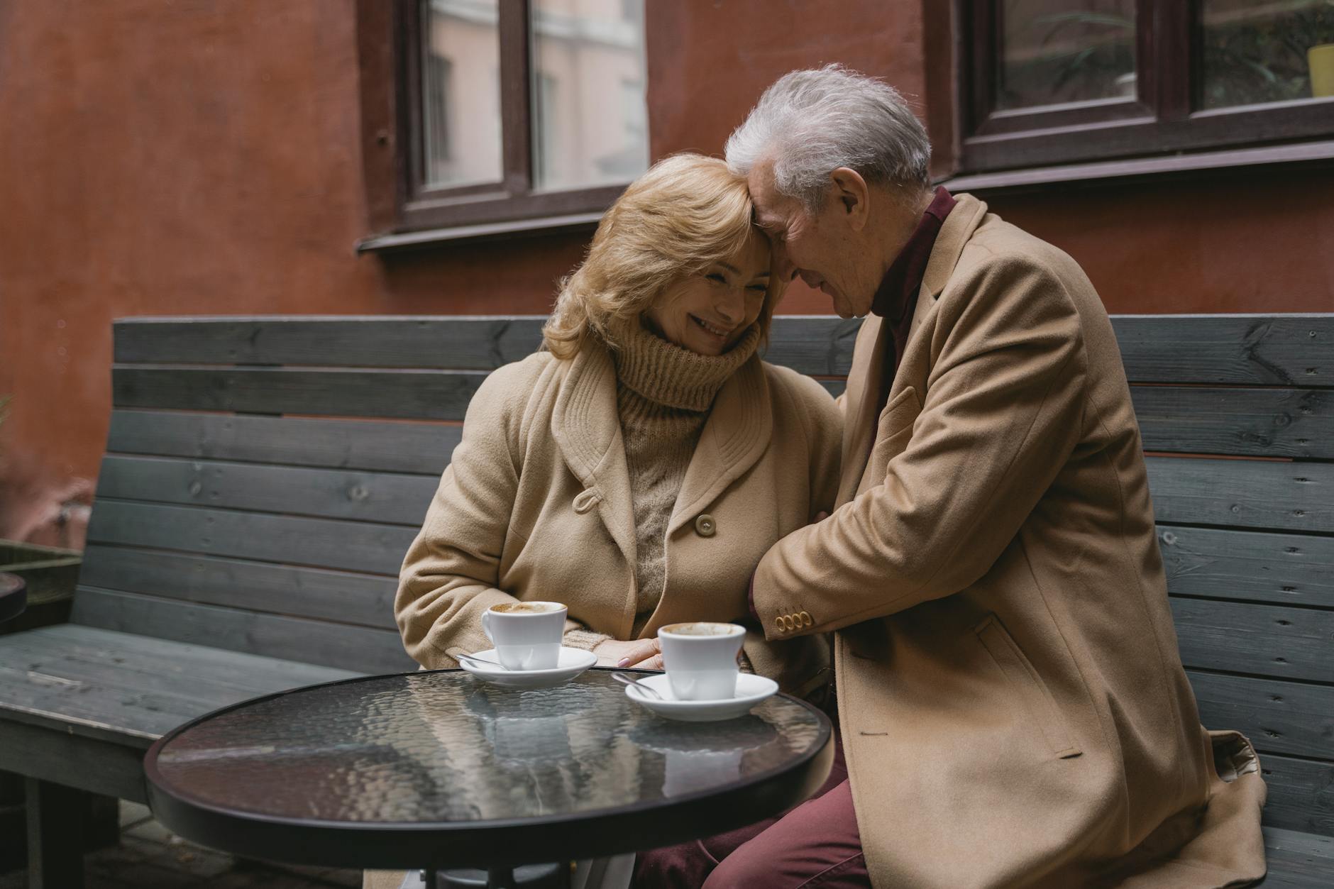 Lovely elderly couple sharing coffee on a cozy outdoor bench, expressing warmth and affection. - dating over 40