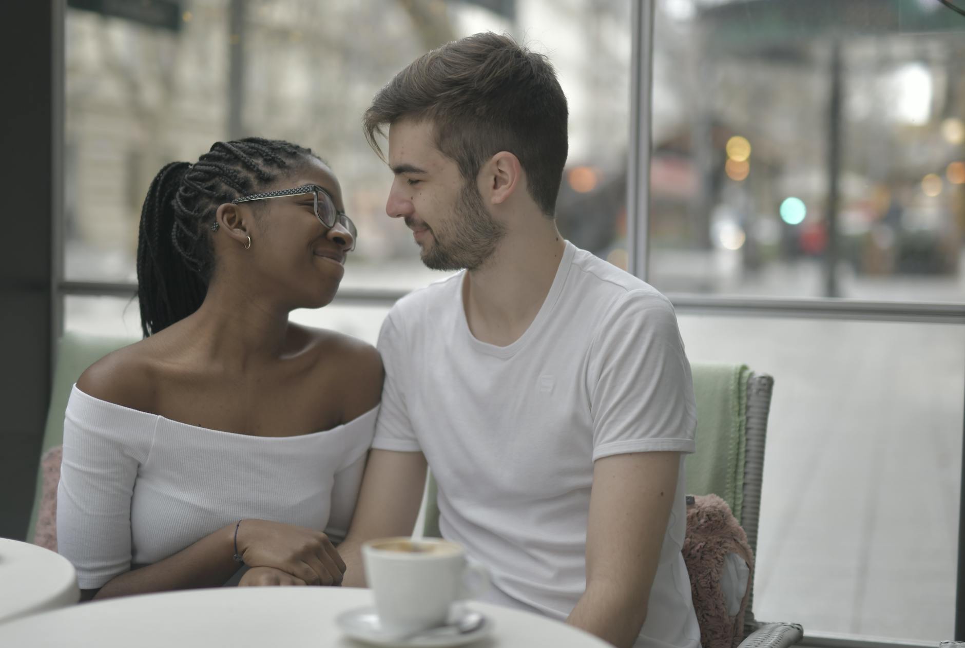 A loving multiracial couple shares a joyful moment over coffee, embracing affection and diversity indoors. - dating in 40s