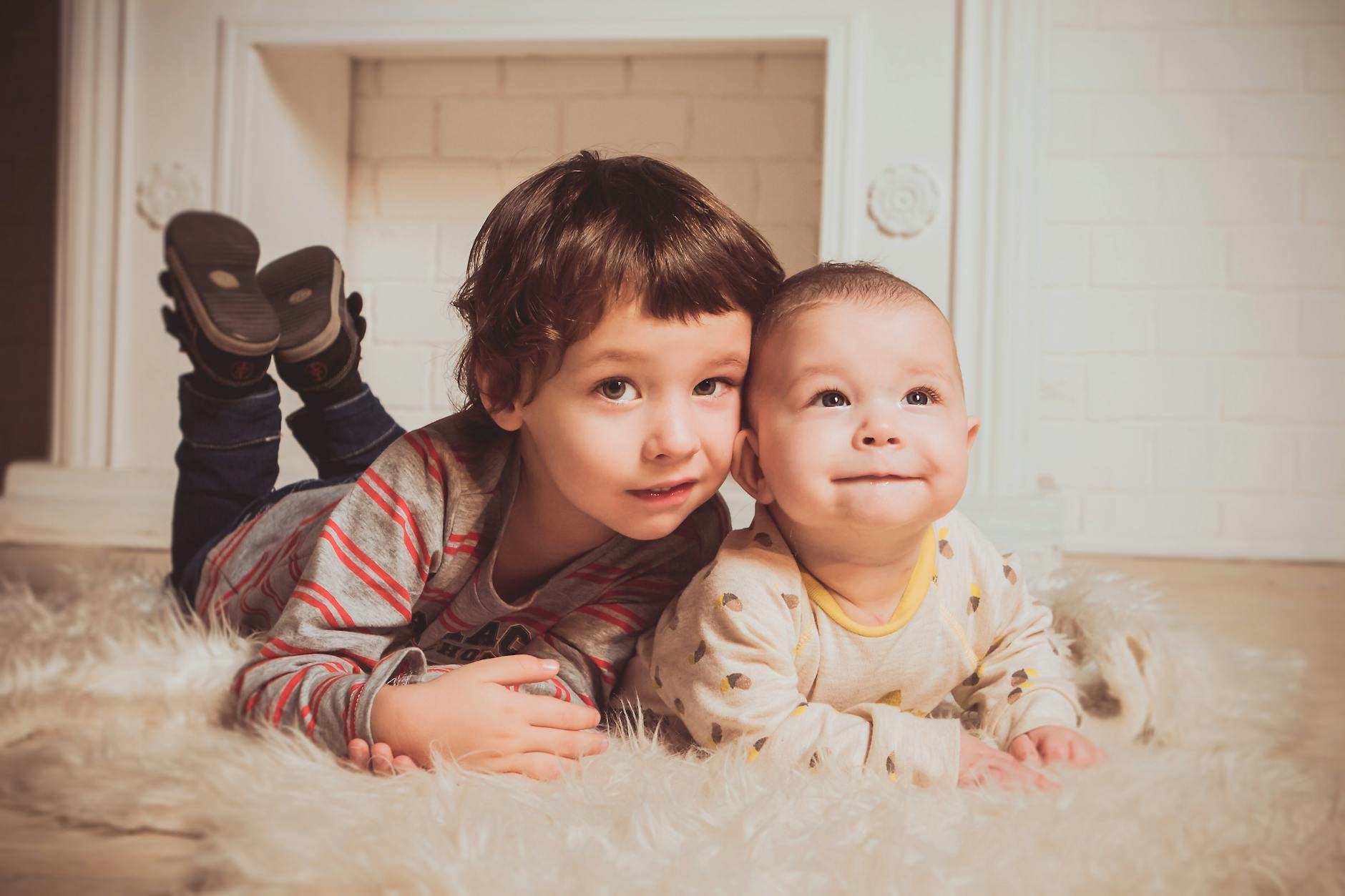 Two young siblings lying on a fluffy rug indoors, exemplifying warmth and family bonding. - family guy sibling rivalry