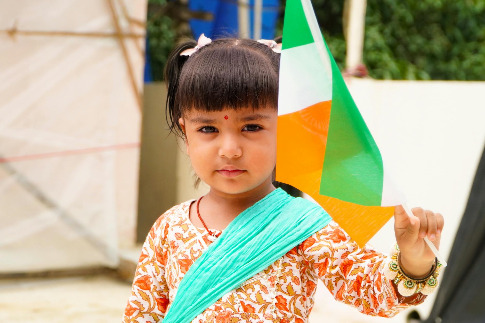 Portrait of a cute child holding the Indian flag outdoors, celebrating national pride. - fostering child independence