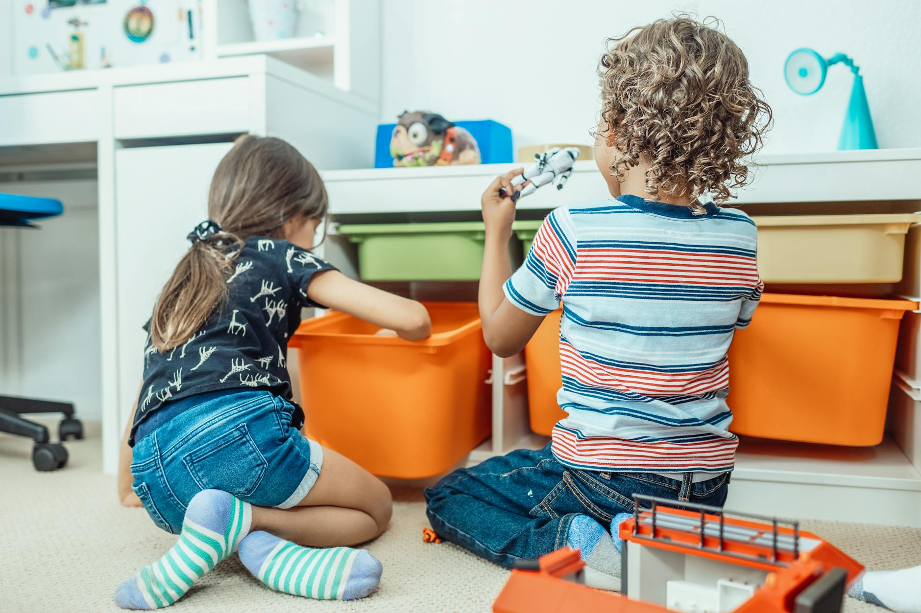 Two kids playing with toys and colorful bins in a playful indoor setting. - fostering independence children