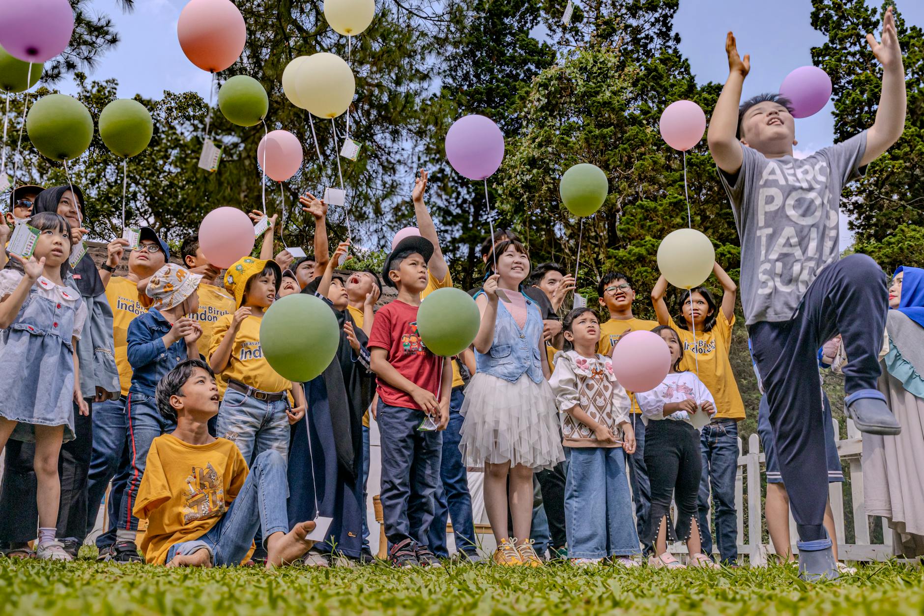 A joyful gathering of children releasing balloons in Bandung, Indonesia, during a festive celebration. - fostering independence children