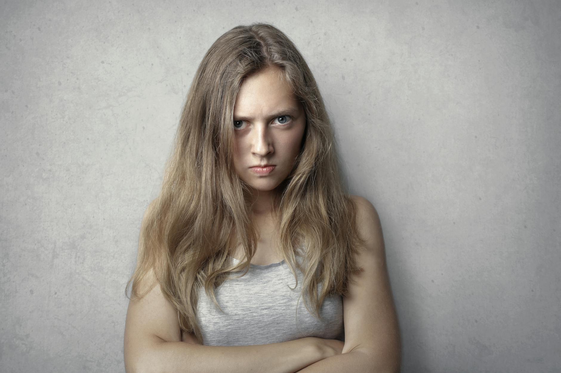 Portrait of a fierce woman with crossed arms and intense expression on a gray background. - free anger management