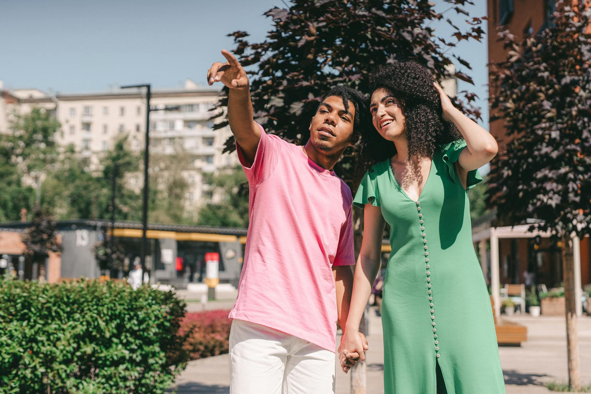 A joyful couple walking outdoors, holding hands and enjoying a sunny day together. - green flags relationship