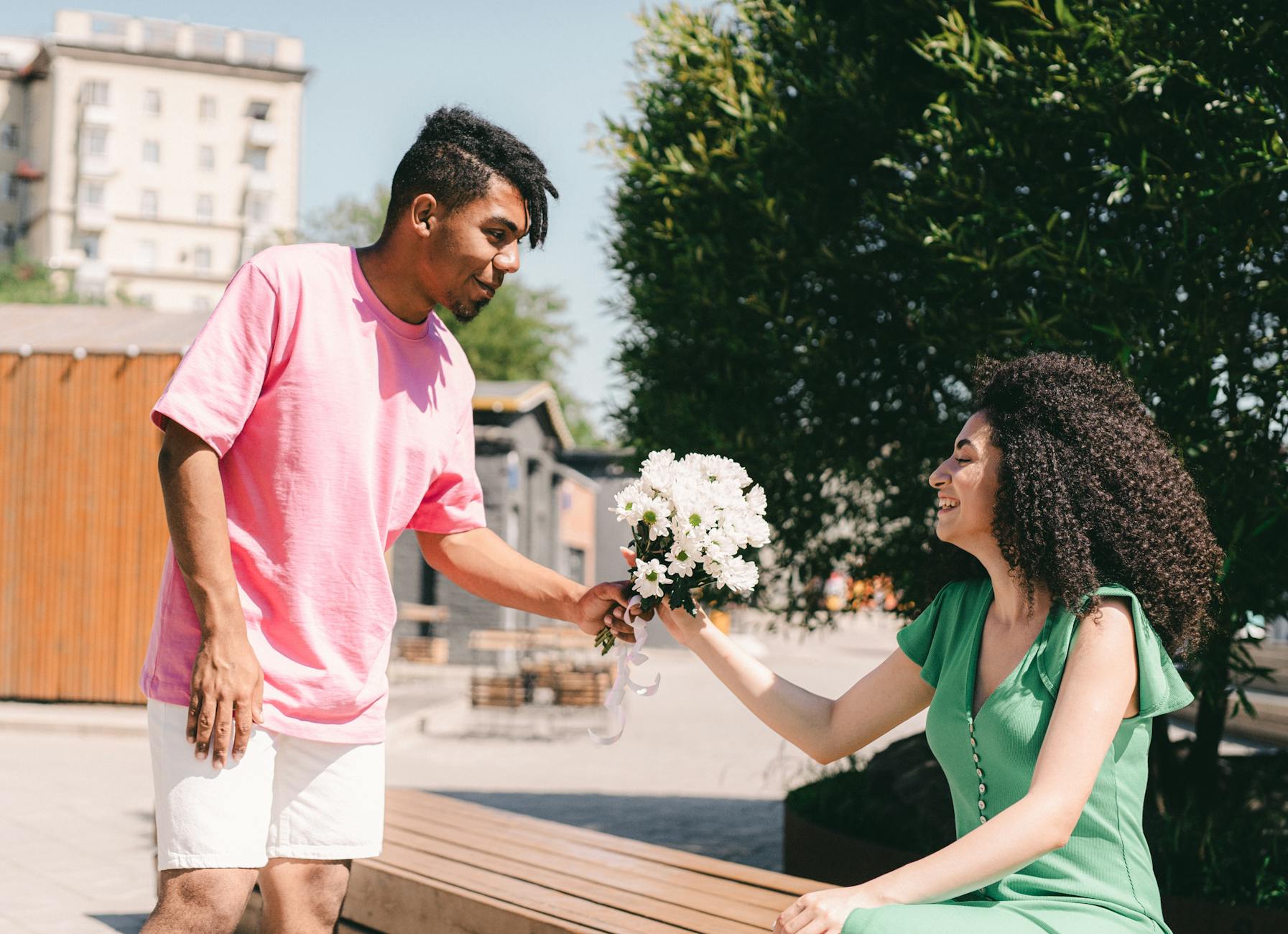 A man gives a bouquet of flowers to a smiling woman outdoors, symbolizing love and romance. - green flags relationship