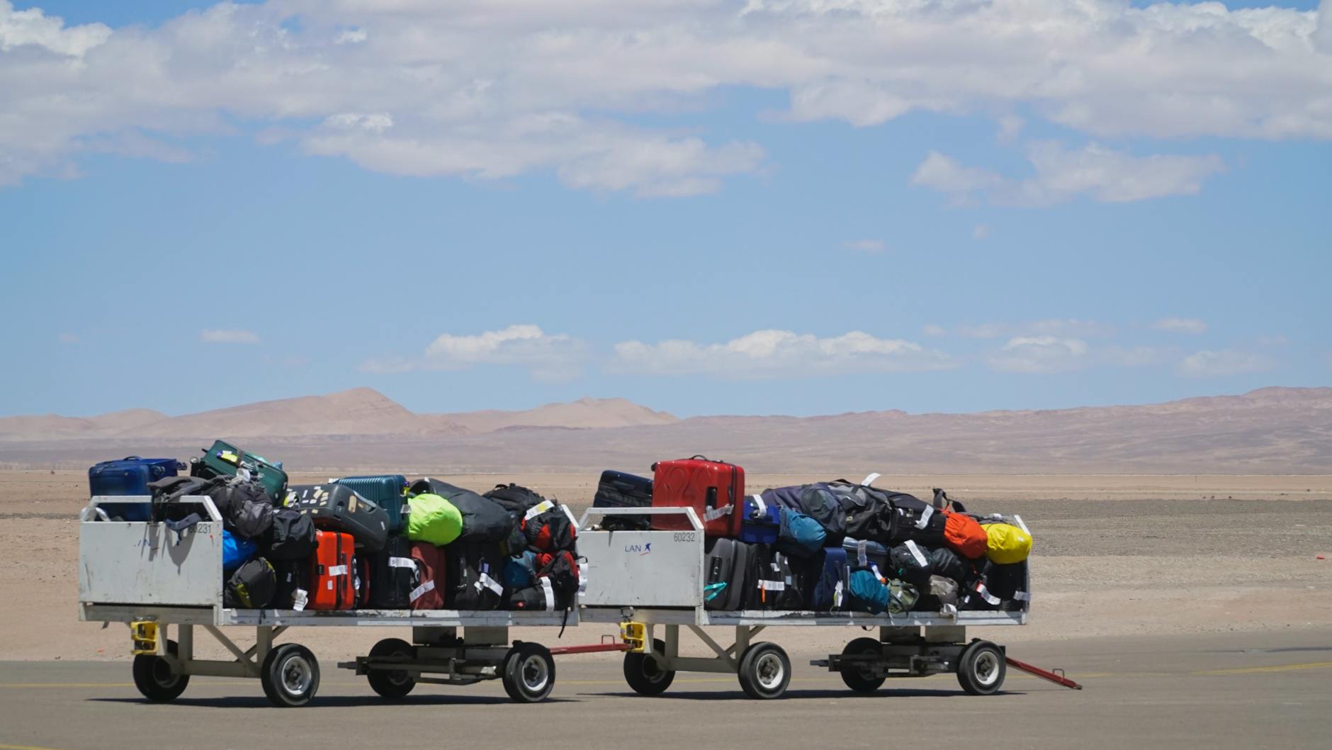 Luggage carts at airport loaded with colorful bags under clear sky. Outdoor travel scene. - letting go of baggage