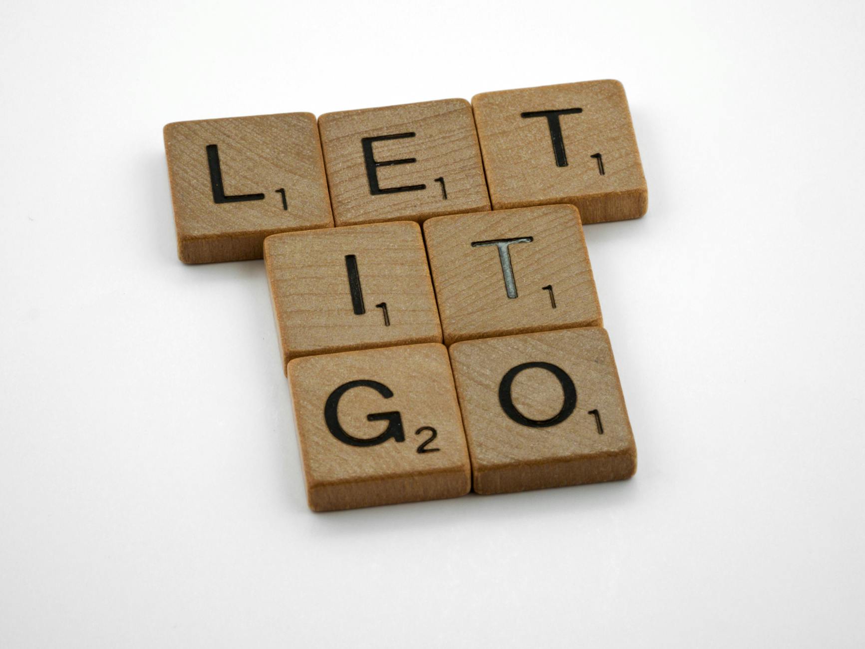Wooden letter tiles spelling 'Let It Go' on a white surface for inspiration. - letting go resentment