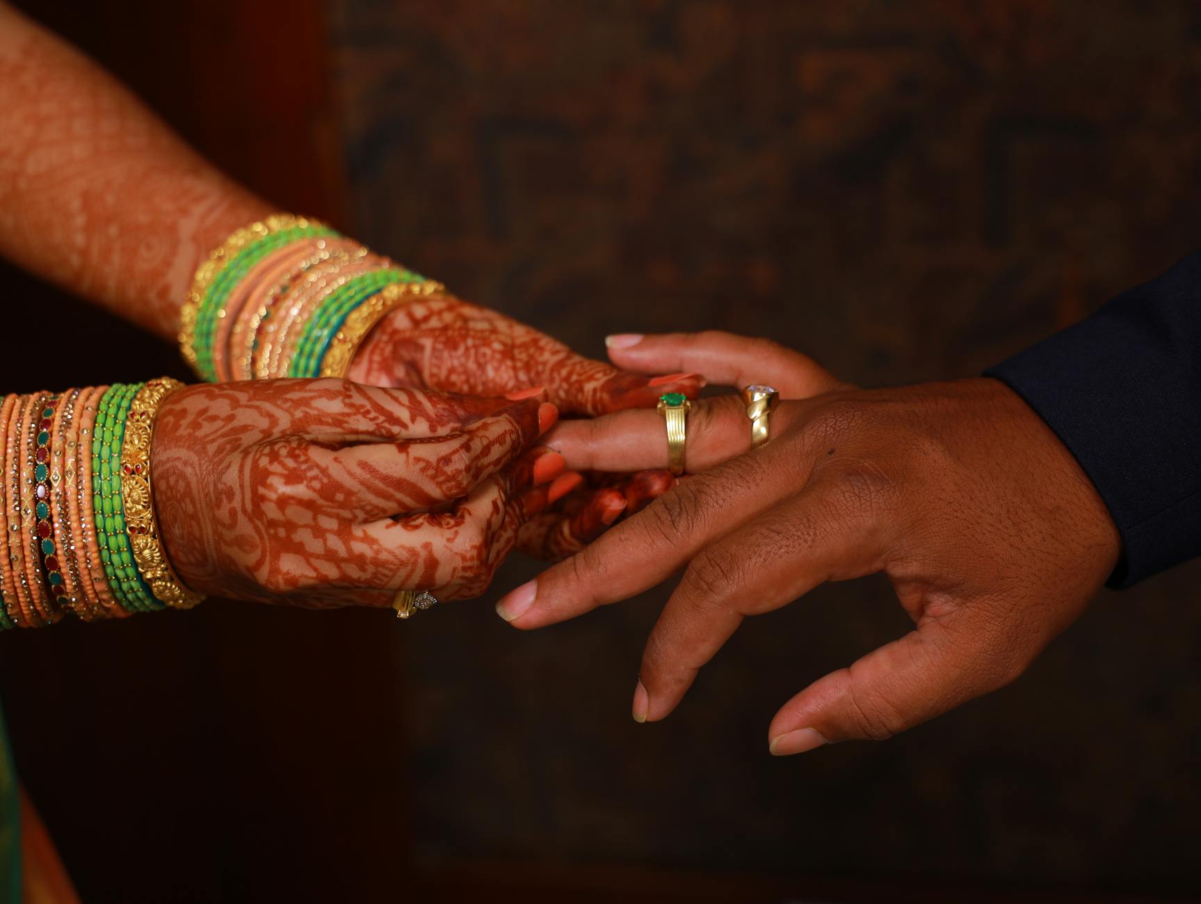 Close-up of a bride and groom exchanging rings with ornate henna and jewelry. - marriage joy rediscovery