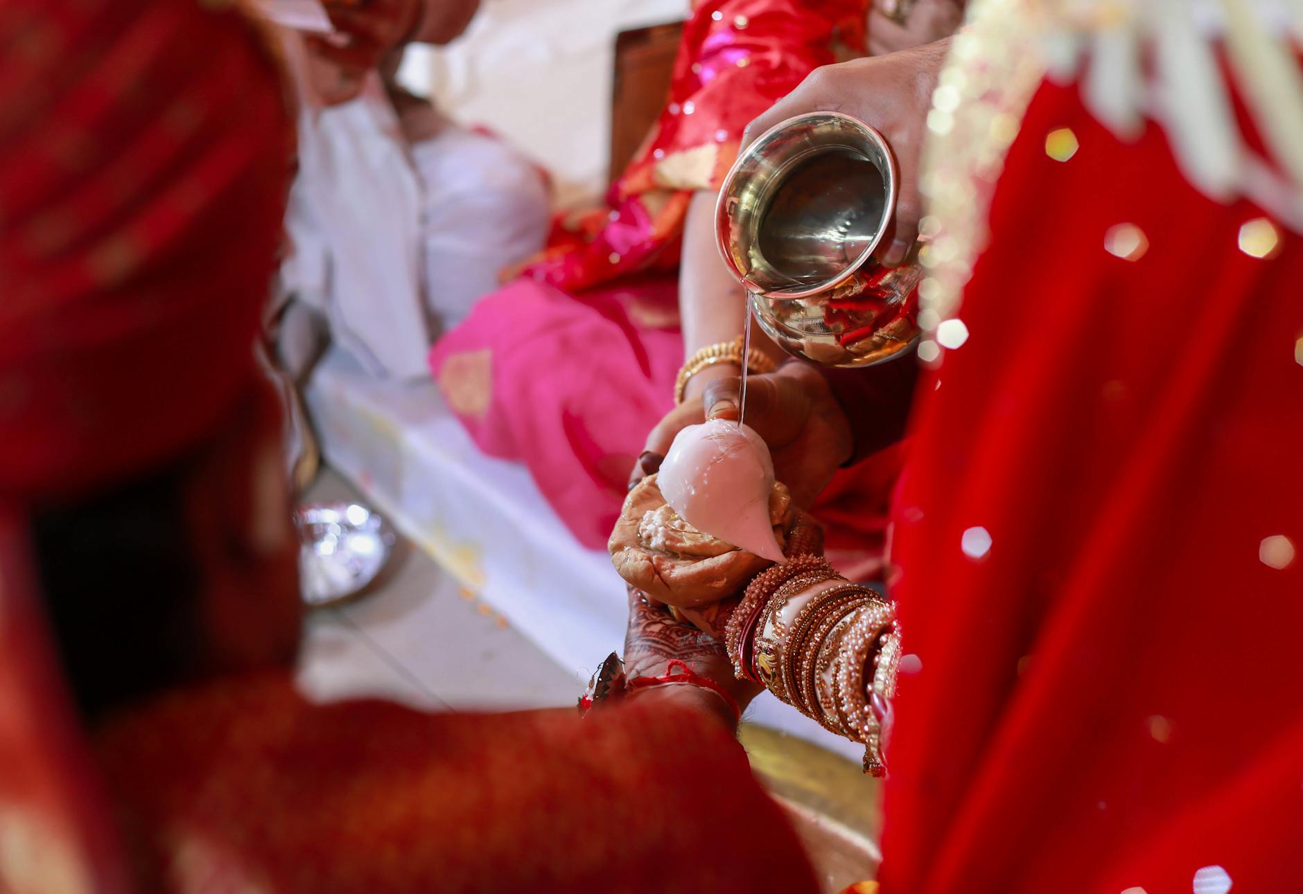Close-up of a ritual pouring ceremony at a traditional Indian wedding, symbolizing spiritual unity. - marriage traditions