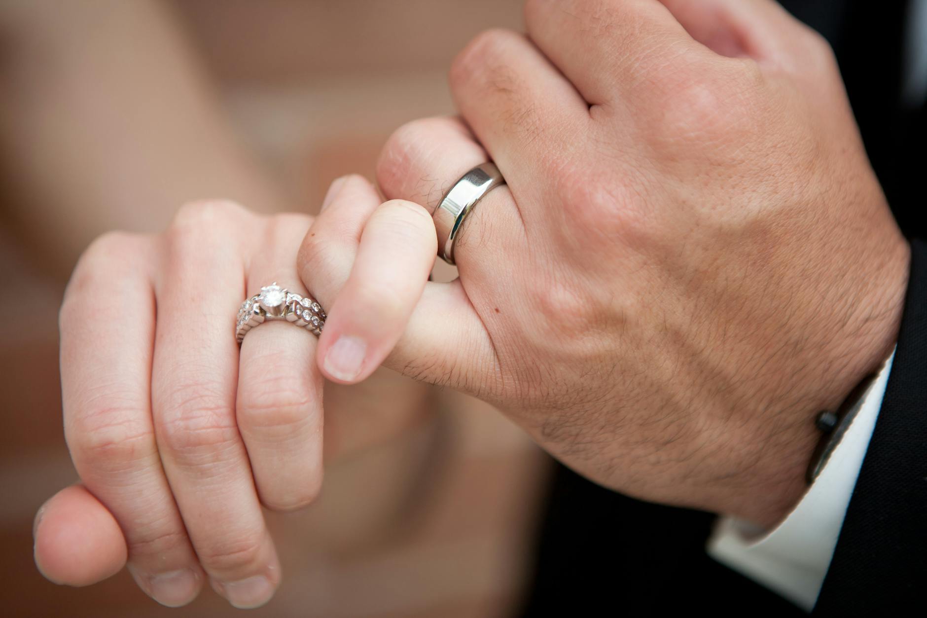 A close-up photo of a couple's hands interlocked, wearing wedding and engagement rings. - marriage tune up