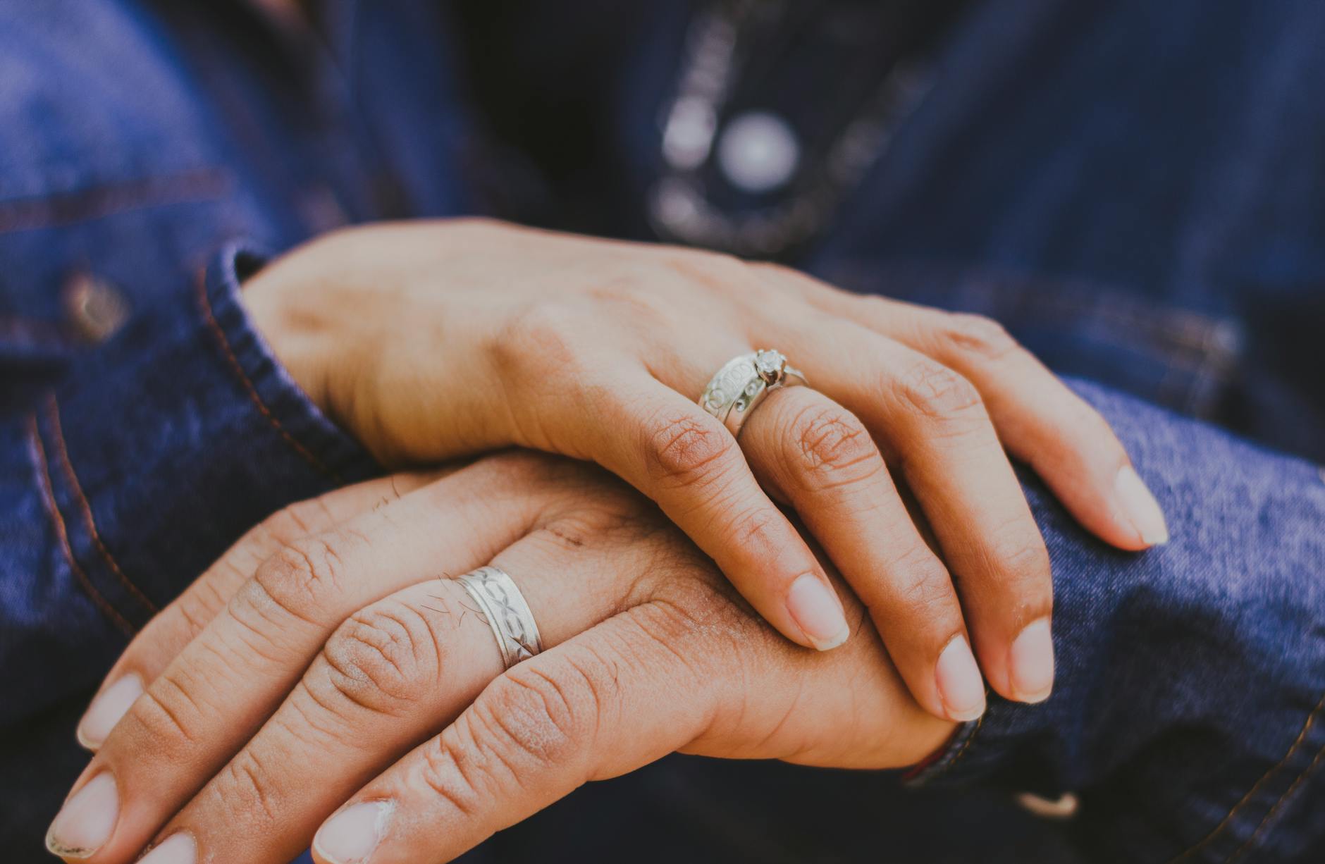 Crop anonymous married couple in similar denim shirts holding hands and demonstrating rings during daytime - marriage tune up