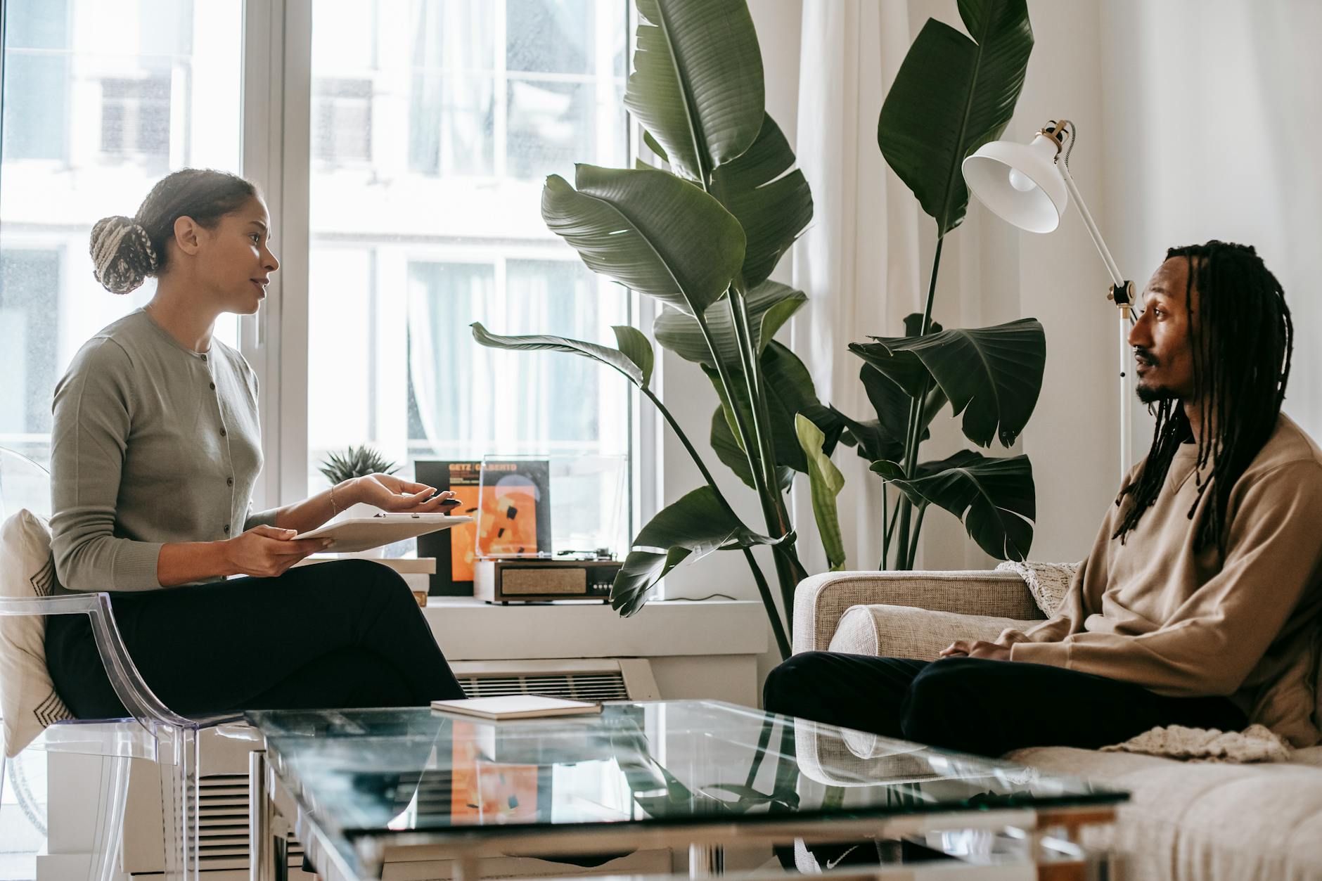 Side view of professional female African American therapist sitting in front of black male patient during psychotherapy session in office - mental well-being therapy