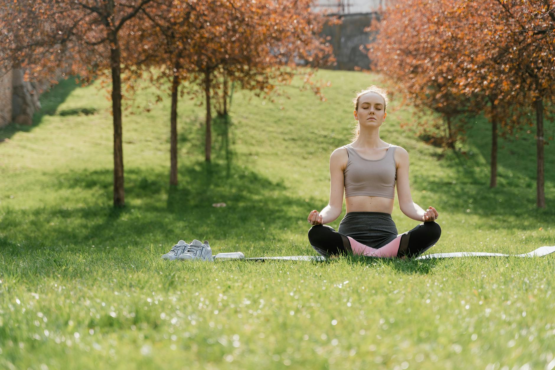 Woman practicing meditation in a sunny park, enhancing wellness and mindfulness. - mindfulness spring allergies