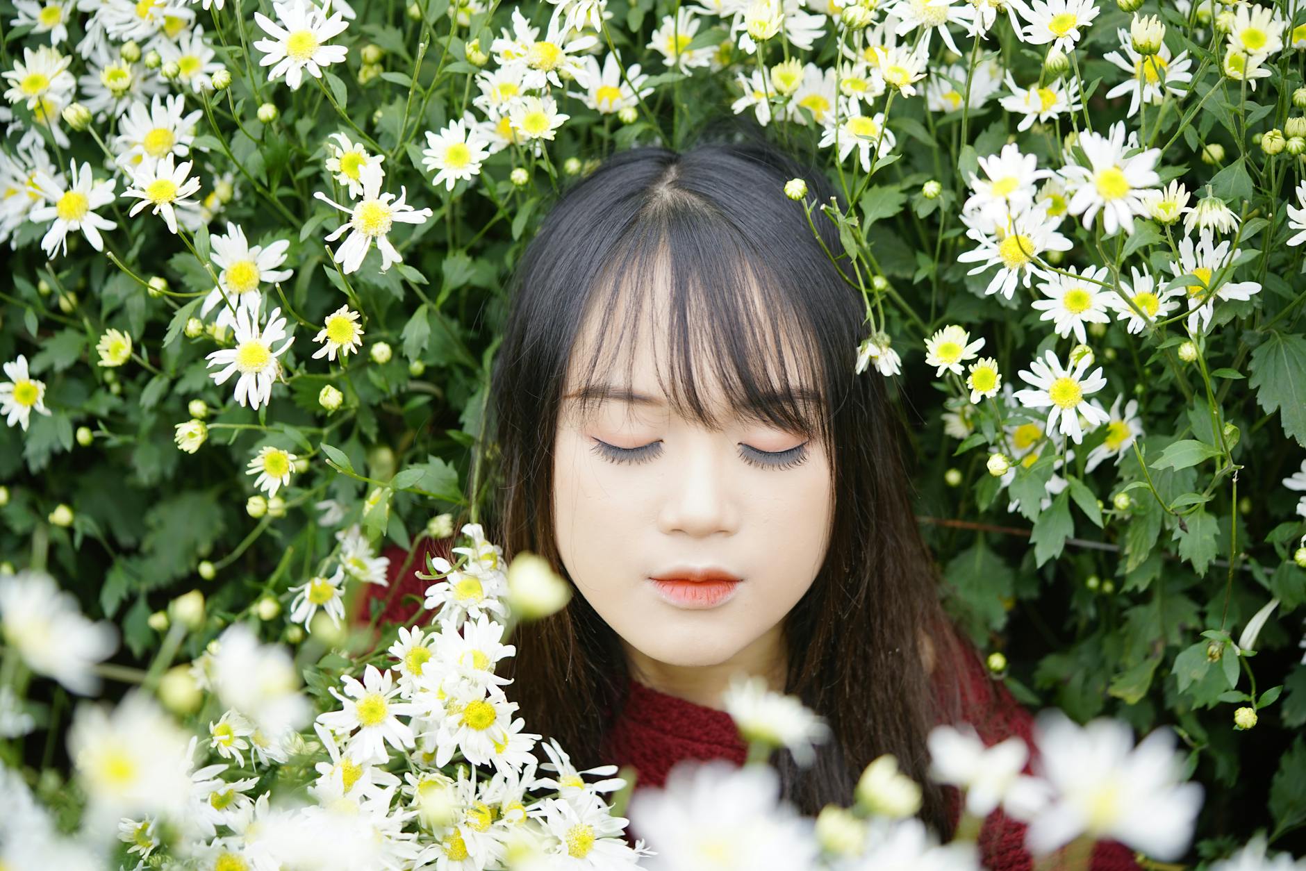 Concentrated ethnic female adolescent with makeup and closed eyes among blossoming white flowers in garden - mindfulness spring allergies