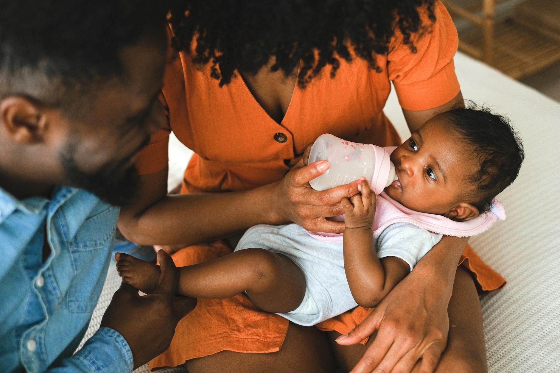 Parents lovingly feeding their baby with a bottle. A warm family moment captured indoors. - new parent self care