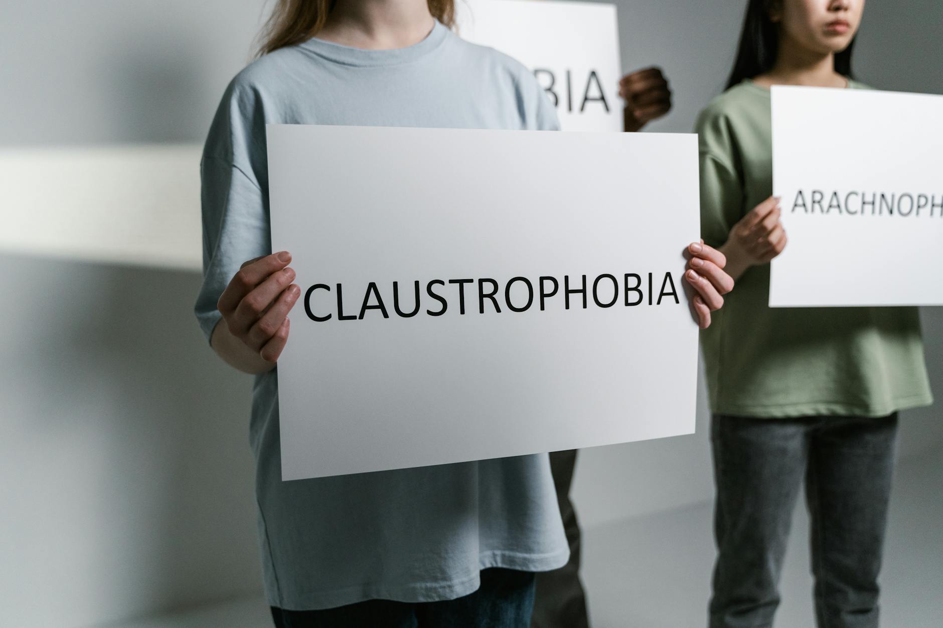Group of individuals holding signs displaying phobia names in a neutral setting. - overcome mental fog