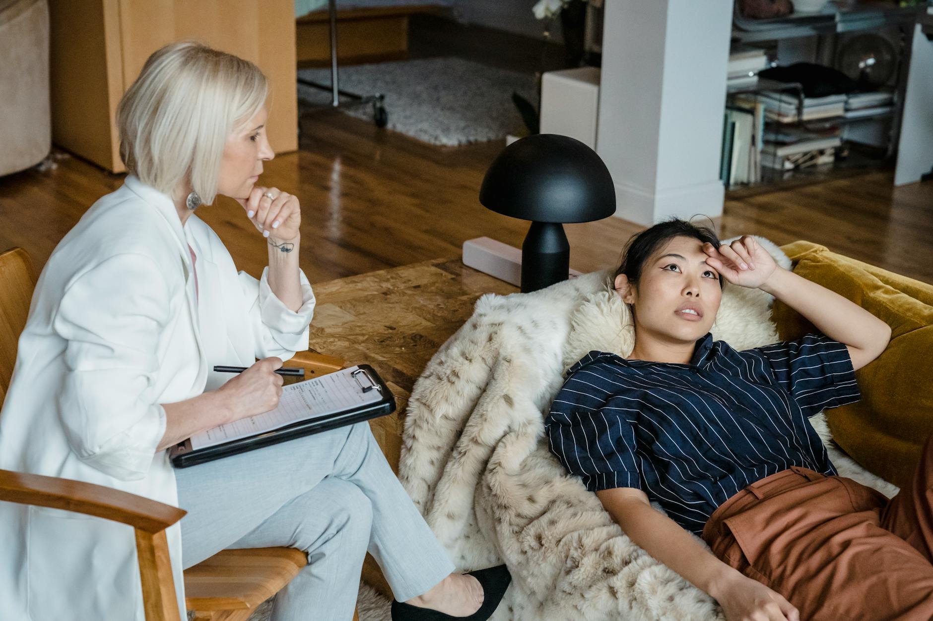 Psychologist listens attentively to a stressed young woman during therapy session. - overthinking therapy
