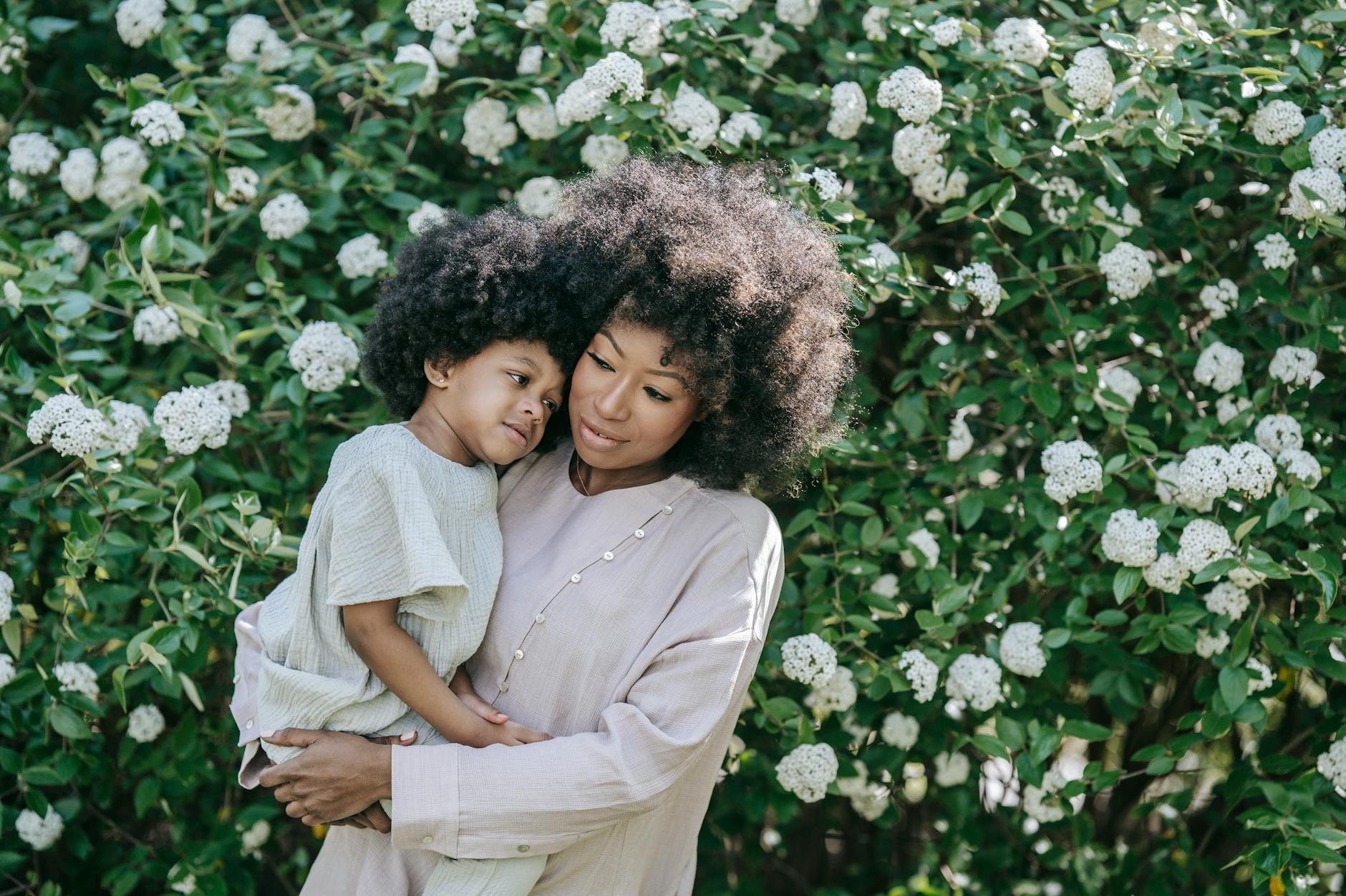 A loving moment between a mother and daughter surrounded by blooming flowers in spring. - parental burnout spring