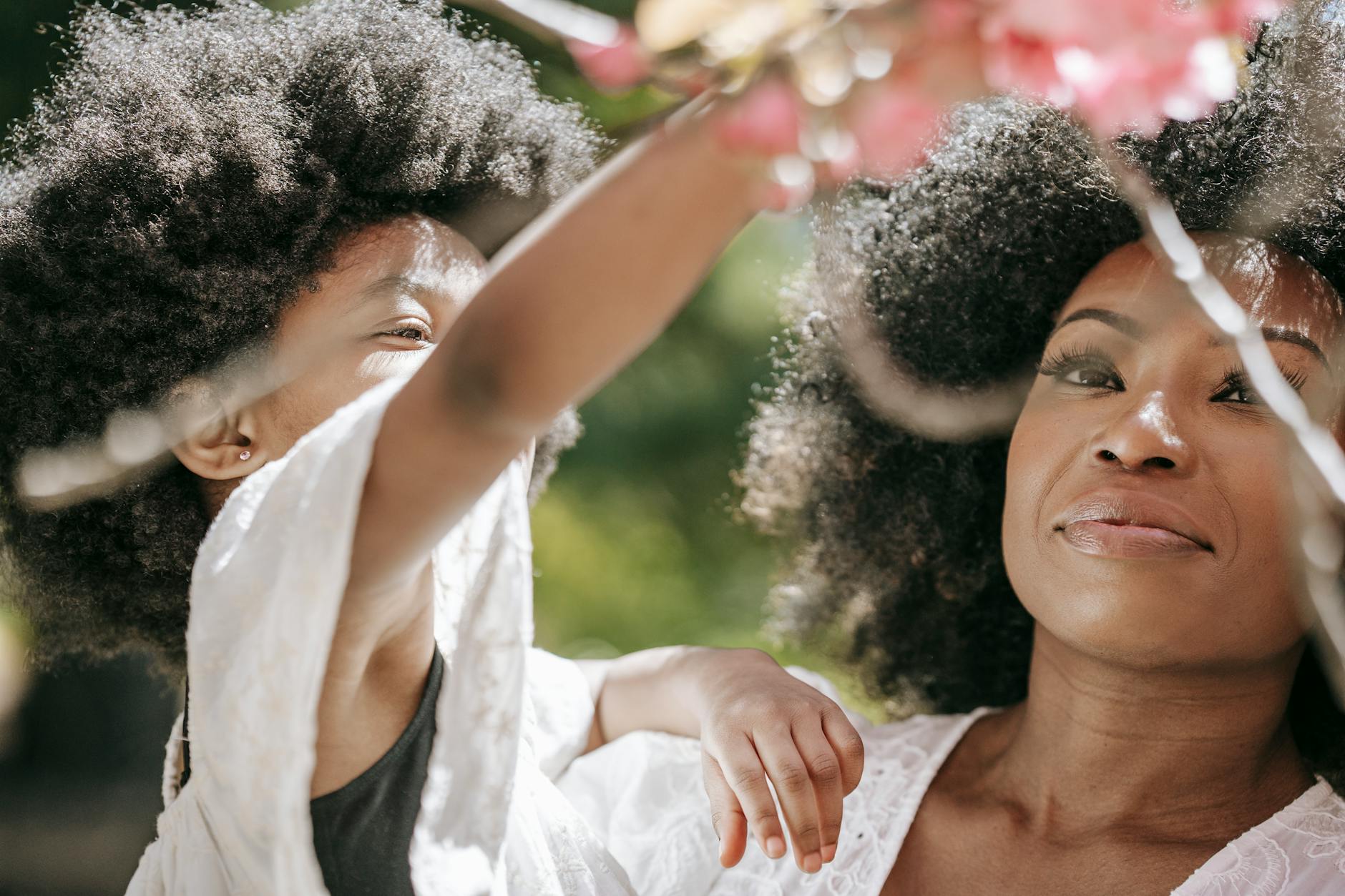 A heartwarming close-up of a mother and daughter enjoying cherry blossoms outdoors. - parental burnout spring