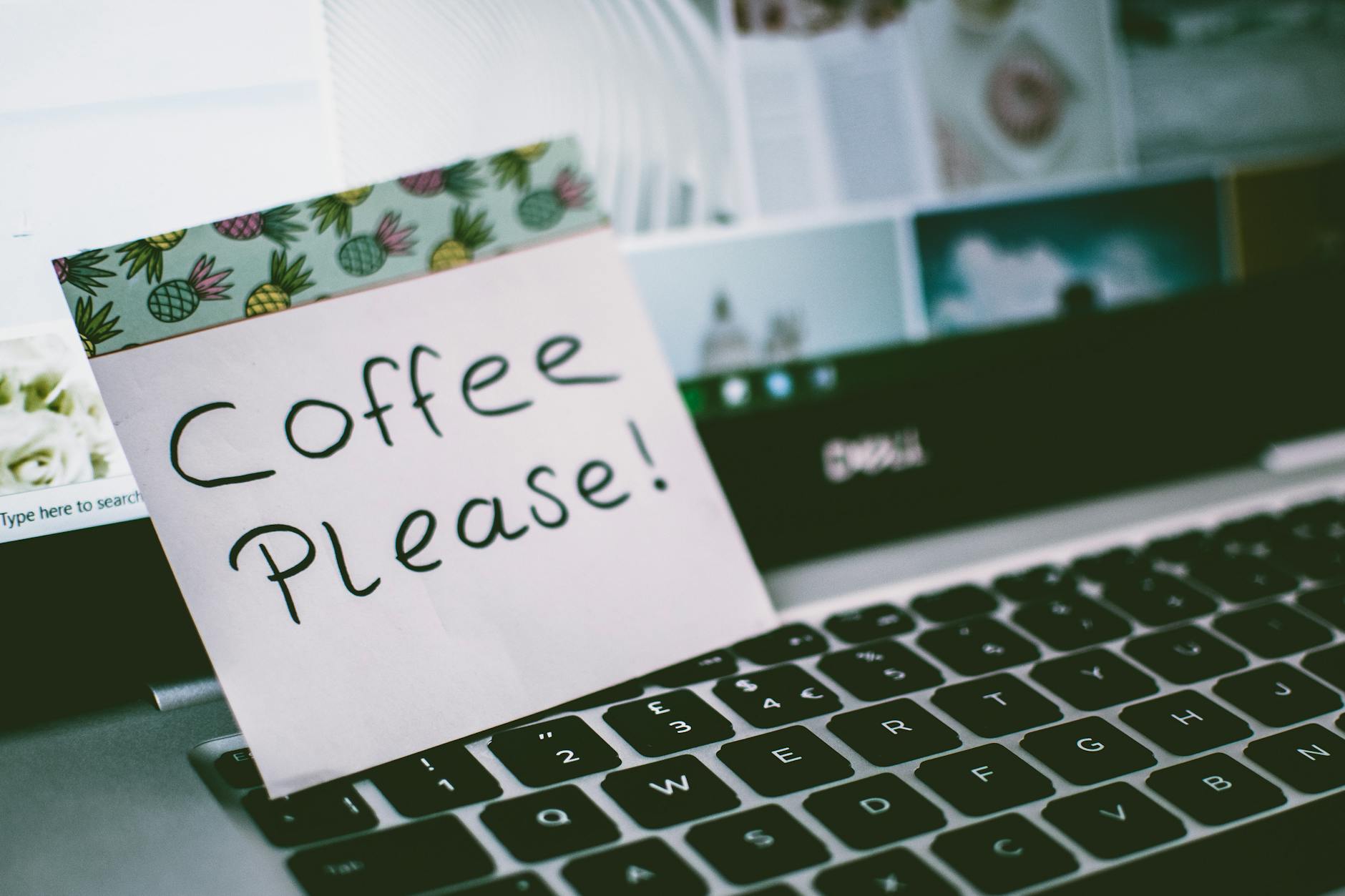 Close-up of a laptop keyboard with a note reading 'Coffee Please!' placed on top, suggesting a coffee break. - post-break communication