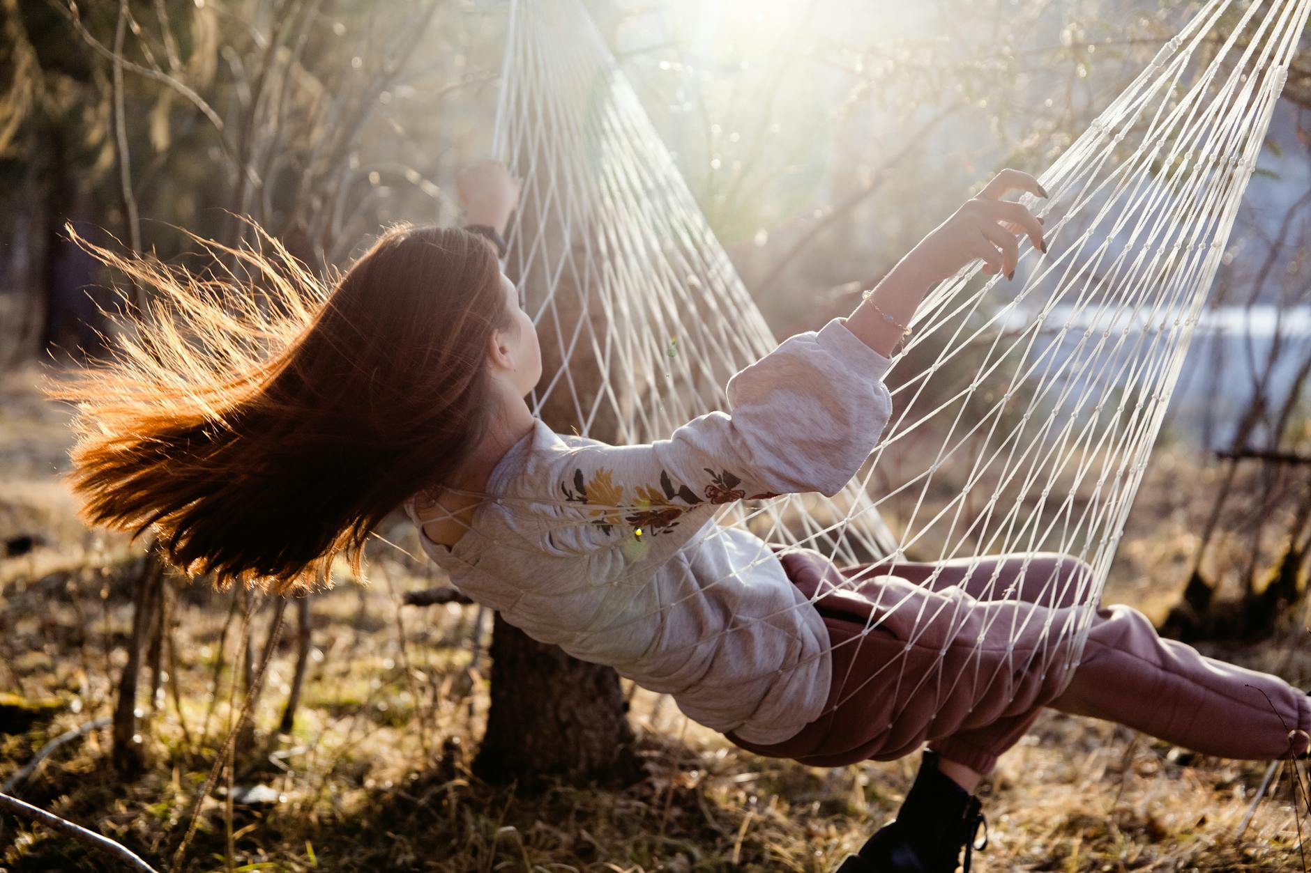 A young woman with red hair swinging in a sunlit hammock outdoors, enjoying nature. - post spring break reconnect