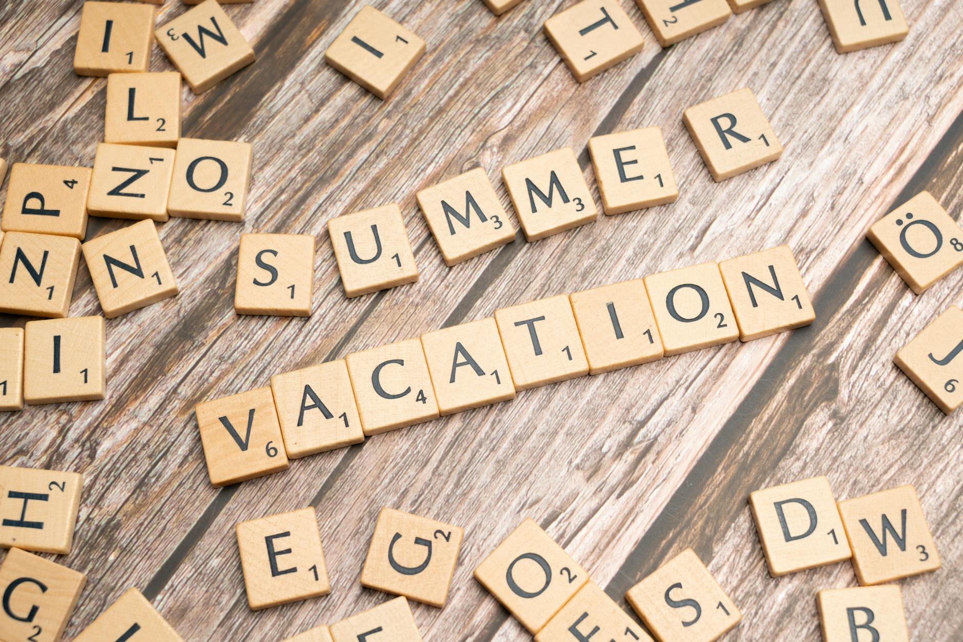 Scrabble tiles spelling 'Summer Vacation' on a rustic wooden background. - post vacation blues