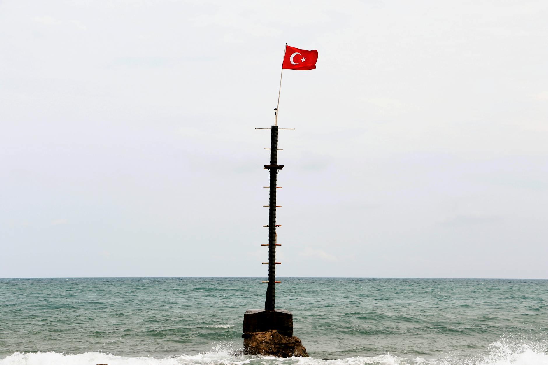 Turkish flag fluttering on isolated seaside mast against a calm sea backdrop. - red flags relationships
