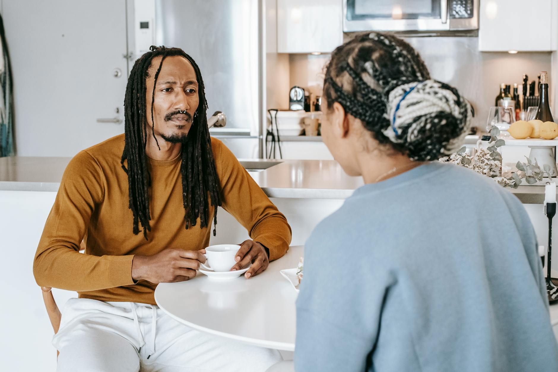 African American male having conversation with African American female in kitchen while having breakfast - relationship needs communication