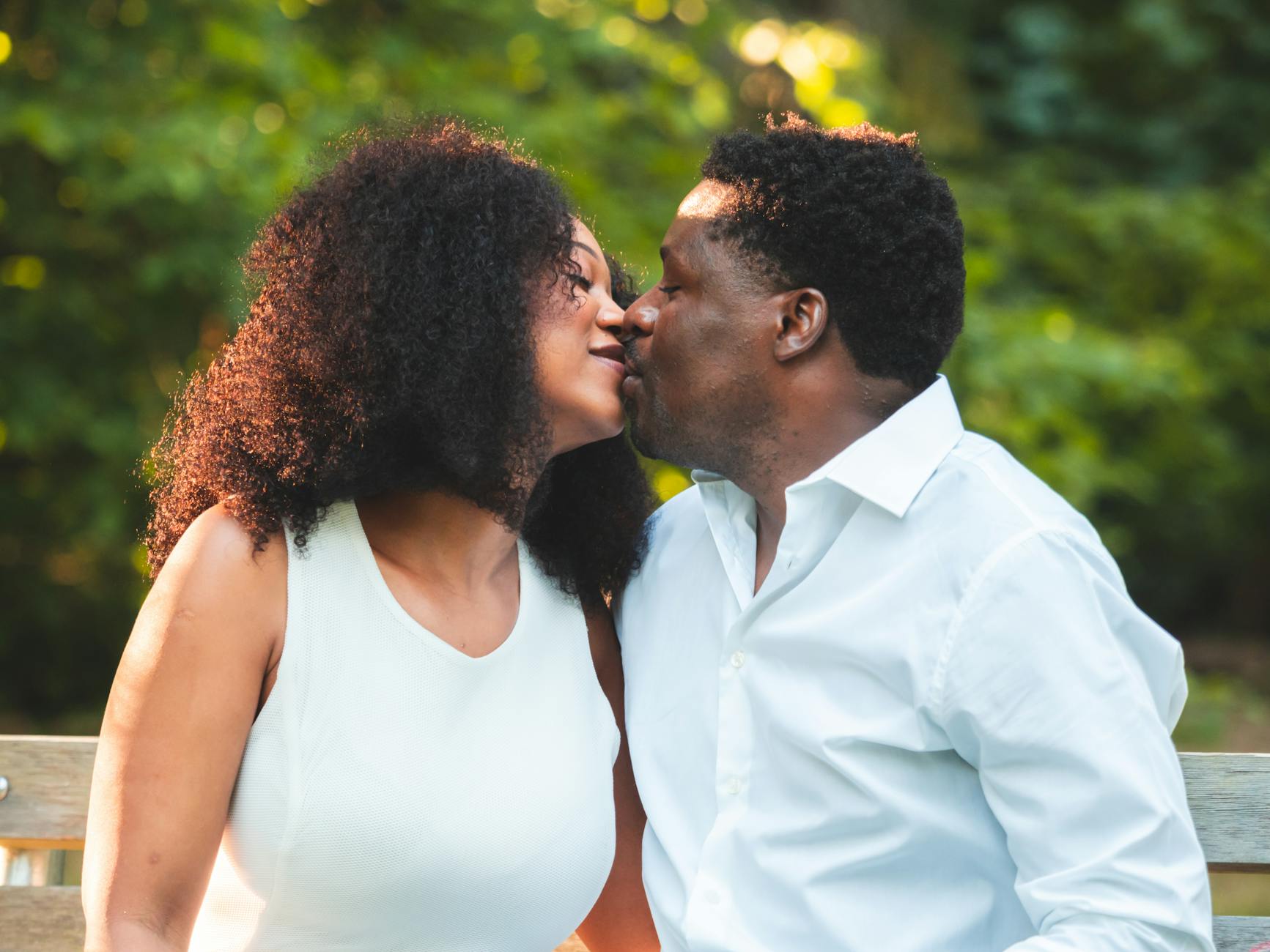A couple enjoying a romantic moment while kissing on a park bench in Seattle. - relationship renewal therapy